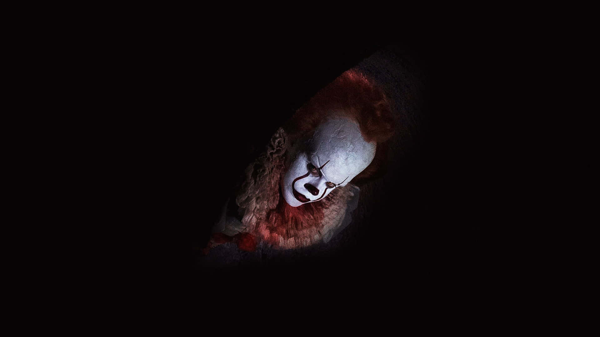 Dark Fear 桌布 壁紙 — 一個帶有紅髮和白色臉部彩繪的威脅性小丑，帶著邪惡的笑容從黑暗中窺視。