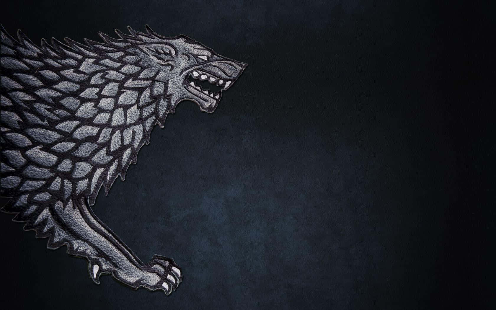 Dire Wolf 桌布 壁紙 — 一個帶有紋理鱗片的兇猛銀色恐狼徽章，在深色紋理背景上咆哮。