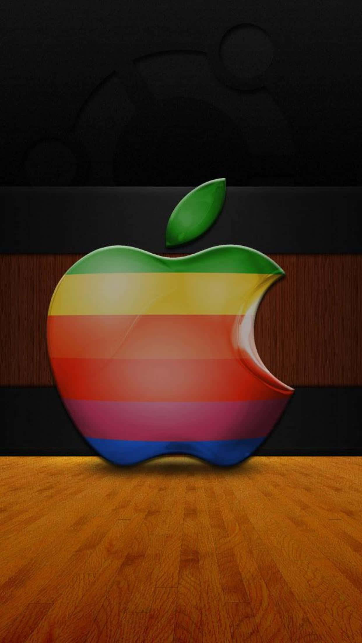 iPhone X Apple Logo 桌布 壁紙 — 一個帶有綠色葉片的光澤彩虹條紋Apple標誌放在木地板上，背景為深色。