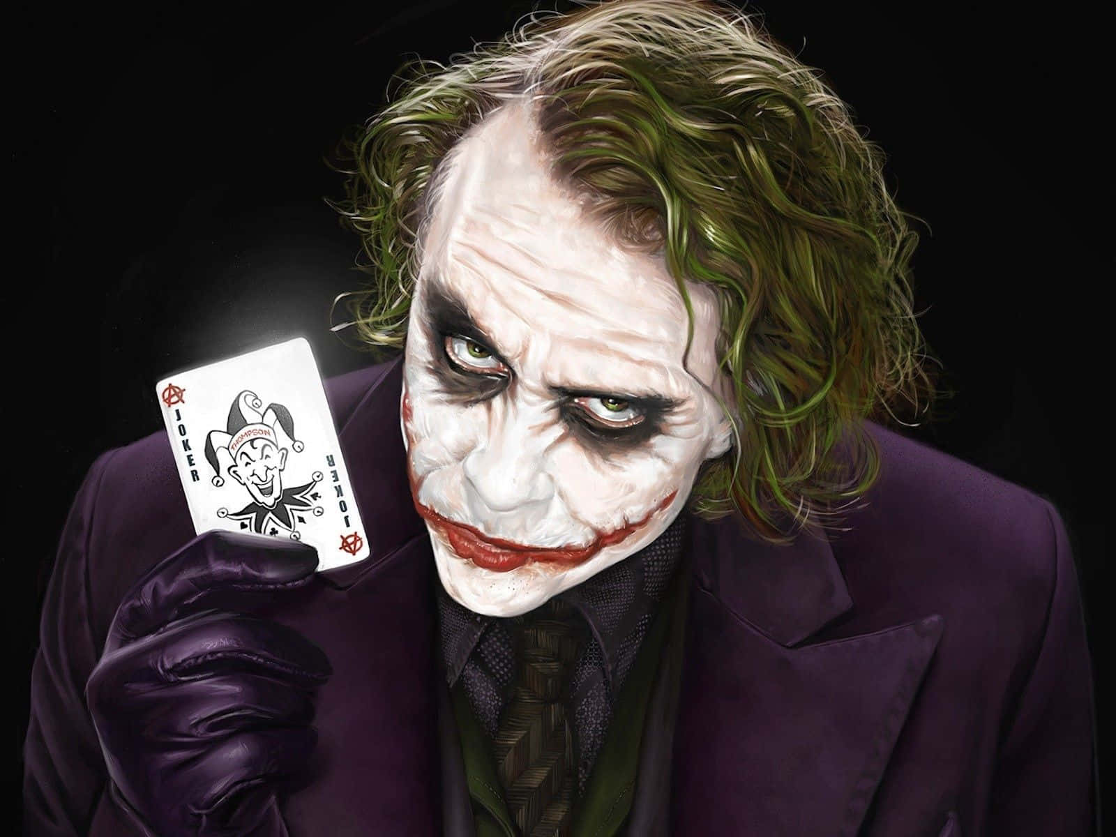 小丑 桌布 壁紙 — 一個帶有綠色頭髮和紫色西裝的威脅性小丑，在黑色背景前拿著一張小丑撲克牌。
