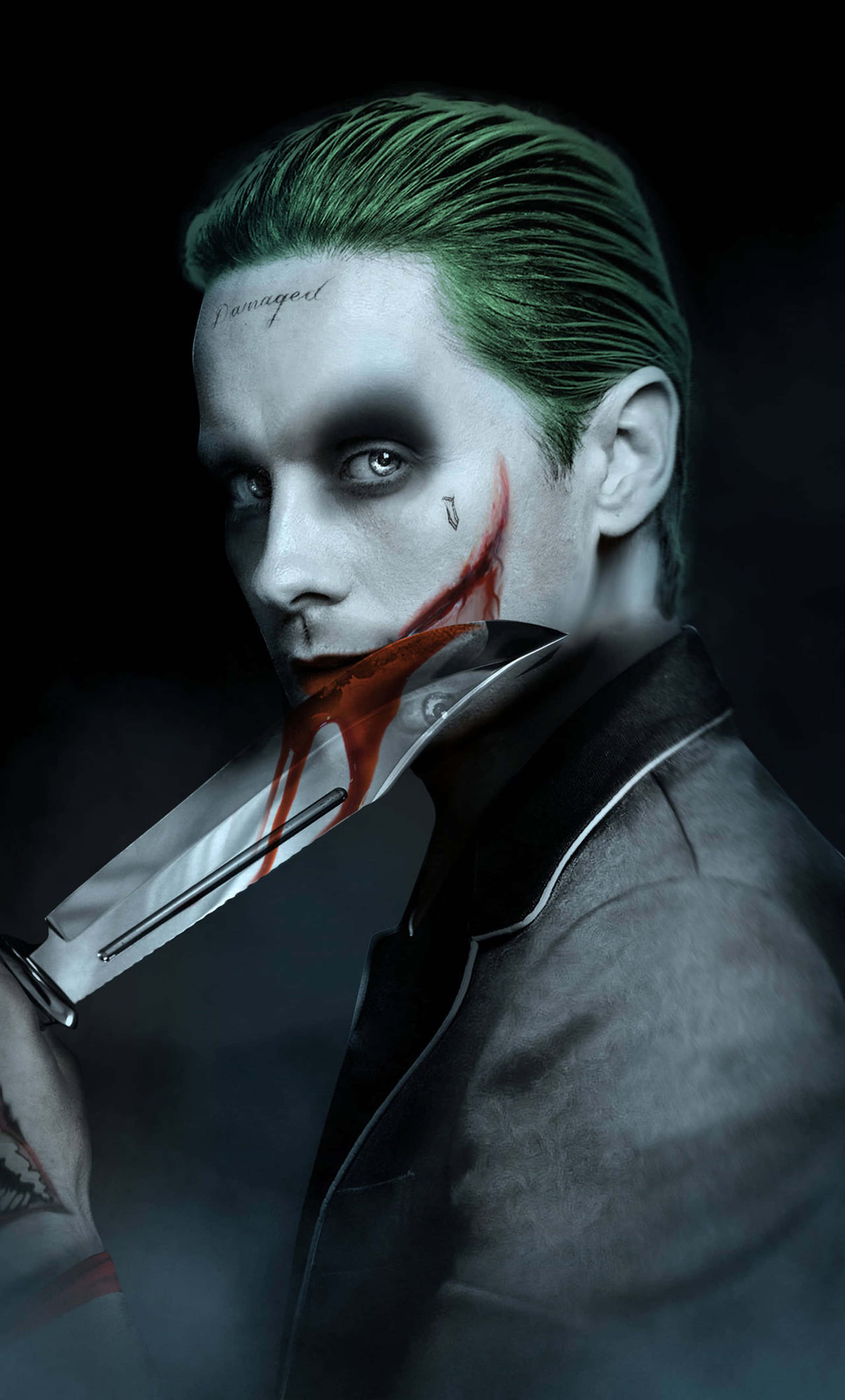 Joker Desktop 桌布 壁紙 — 一個帶有綠色頭髮和血淋淋刀子的威脅性小丑，在黑暗背景下強烈凝視。