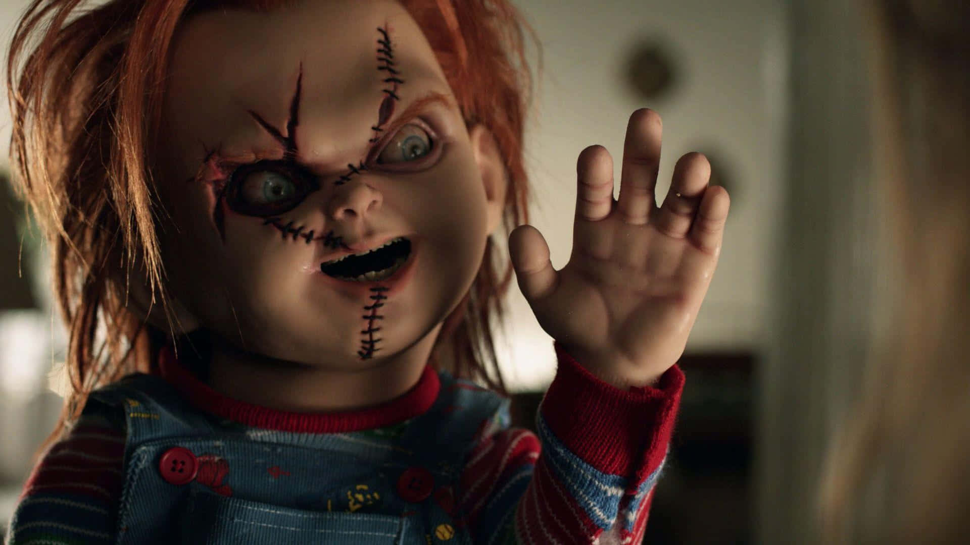 Chucky Doll 桌布 壁紙 — 一個帶有縫合疤痕和狂野眼睛的威脅性娃娃在昏暗的房間裡舉起手。