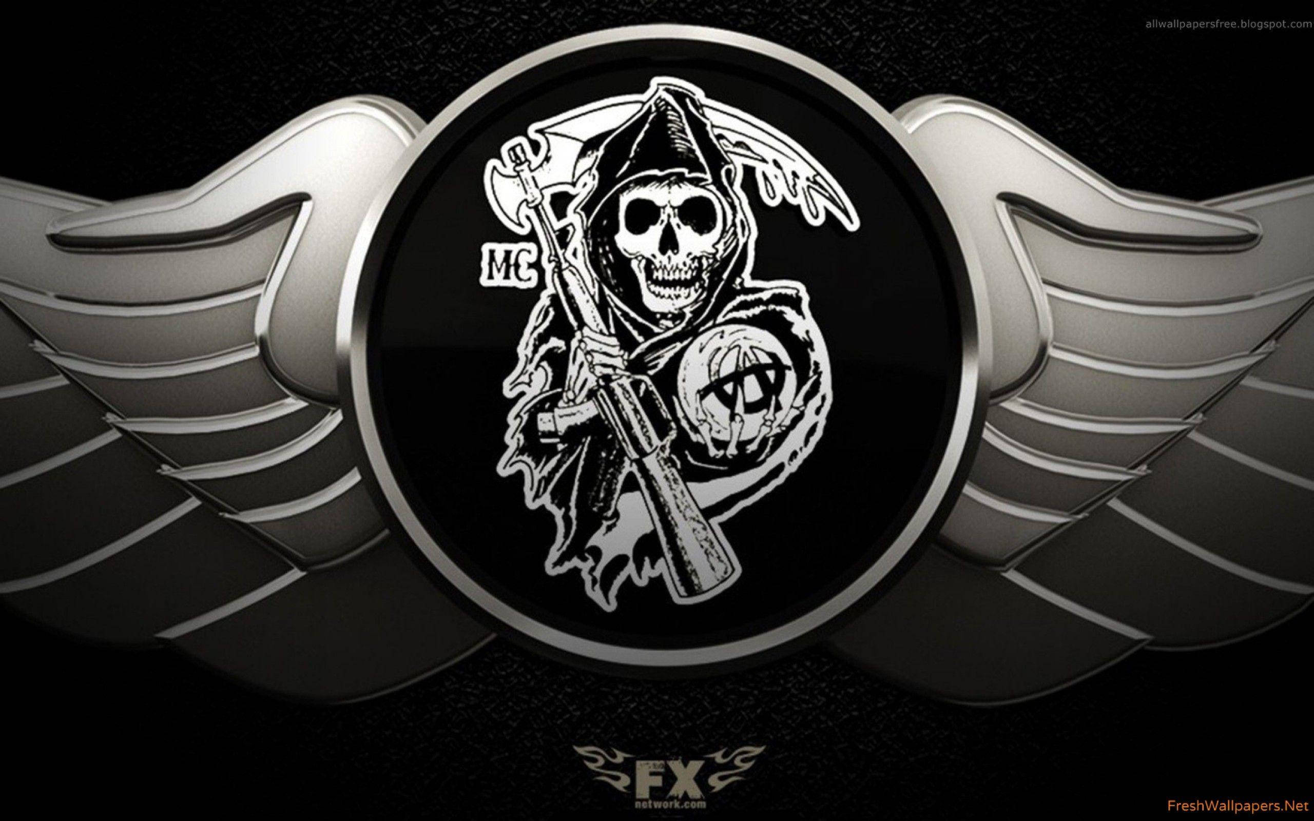 Sons Of Anarchy 桌布 壁紙 — 一個帶有翅膀和步槍的威脅性頭骨，位於金屬徽章中央，背景為深色。