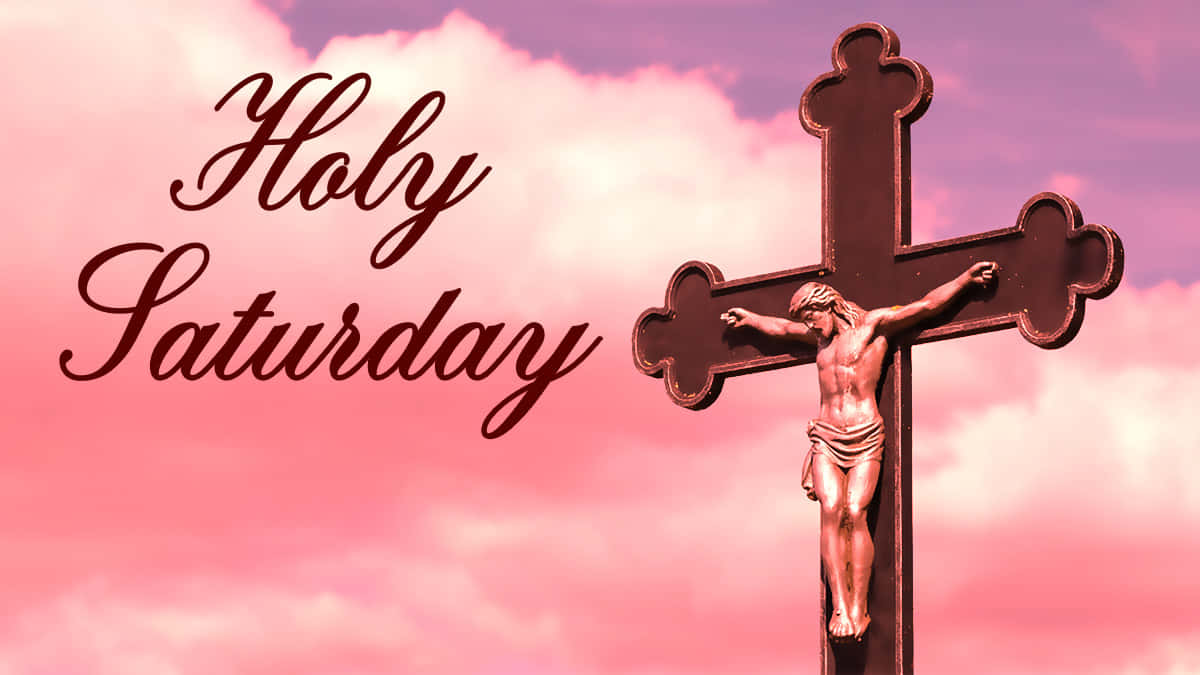 Holy Saturday 桌布 壁紙 — 一個帶有耶穌基督的青銅十字架，矗立在柔和粉紅和紫色雲彩的天空前，並以優雅草書寫有 'Holy Saturday'。