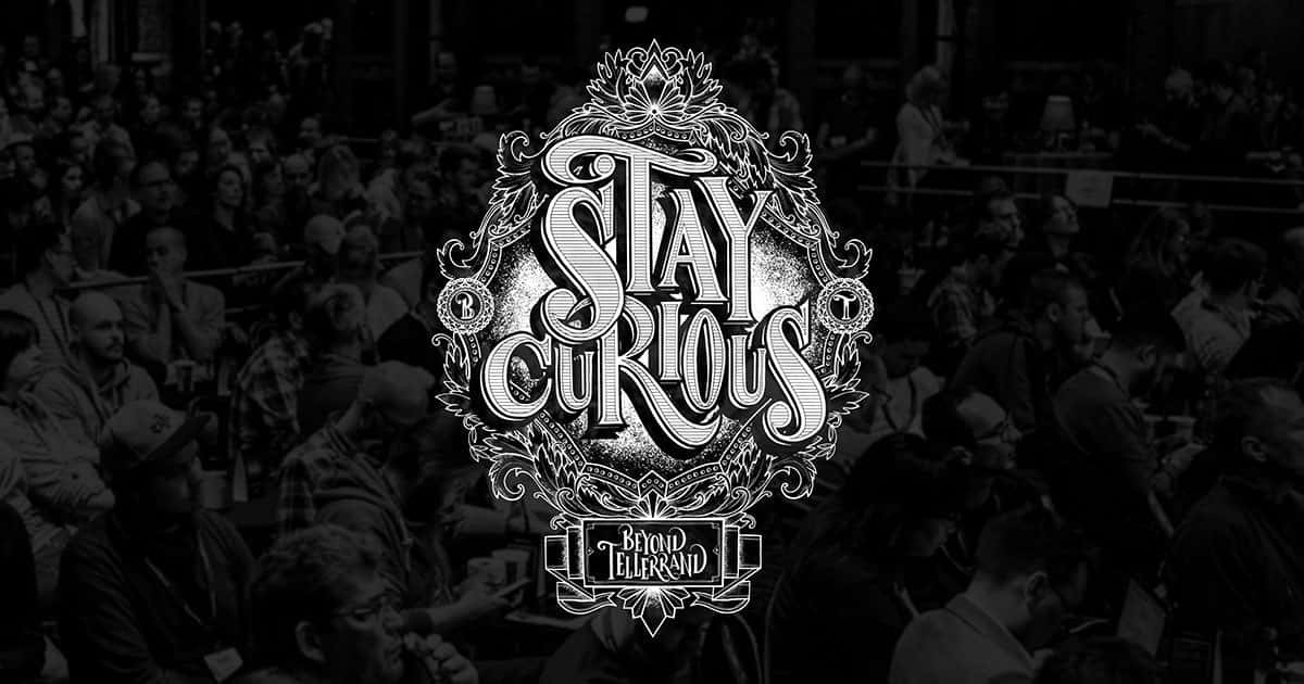 Monochrome 桌布 壁紙 — 一個帶有花卉細節的華麗白色「Stay Curious」標誌，疊加在一張坐著觀眾的黑白照片上。