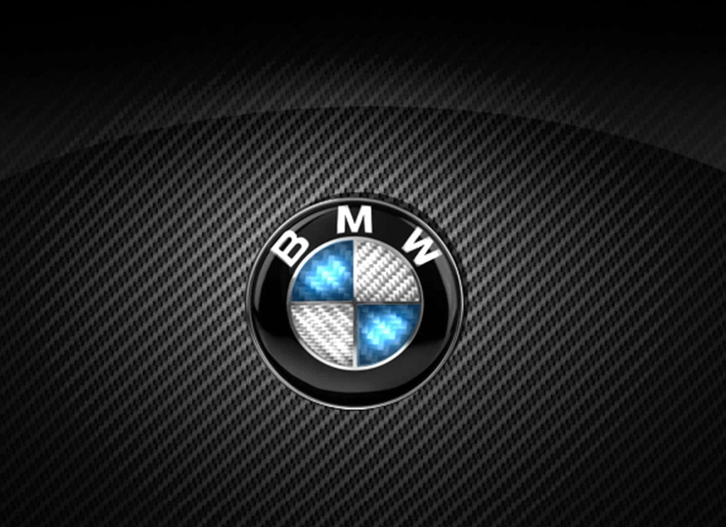 Bmw Logo 桌布 壁紙 — 一個帶有藍色和銀色象限的光亮BMW標誌，居中放置在深色碳纖維紋理背景上。