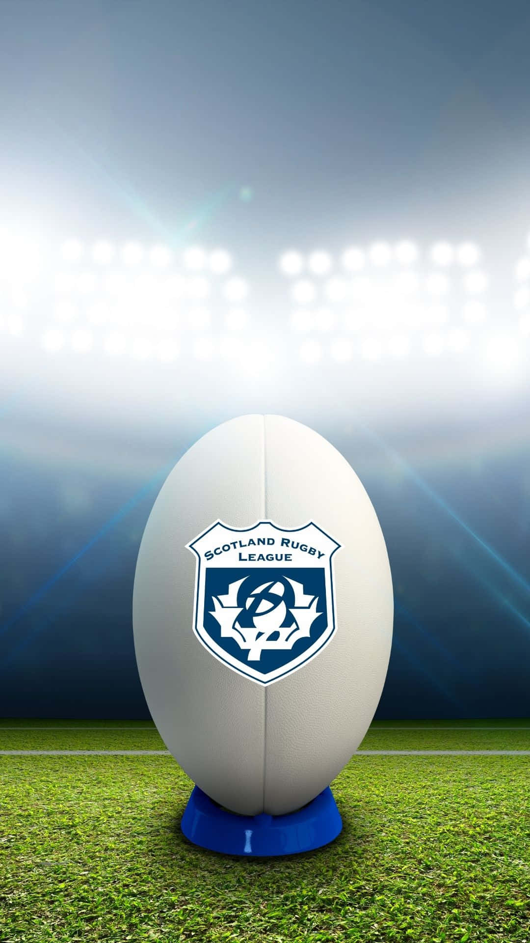 Scotland Rugby 桌布 壁紙 — 一個帶有蘇格蘭橄欖球聯賽徽章的白色橄欖球，在明亮的球場燈光下，放置在藍色底座上，底座位於充滿活力的綠色草地上。