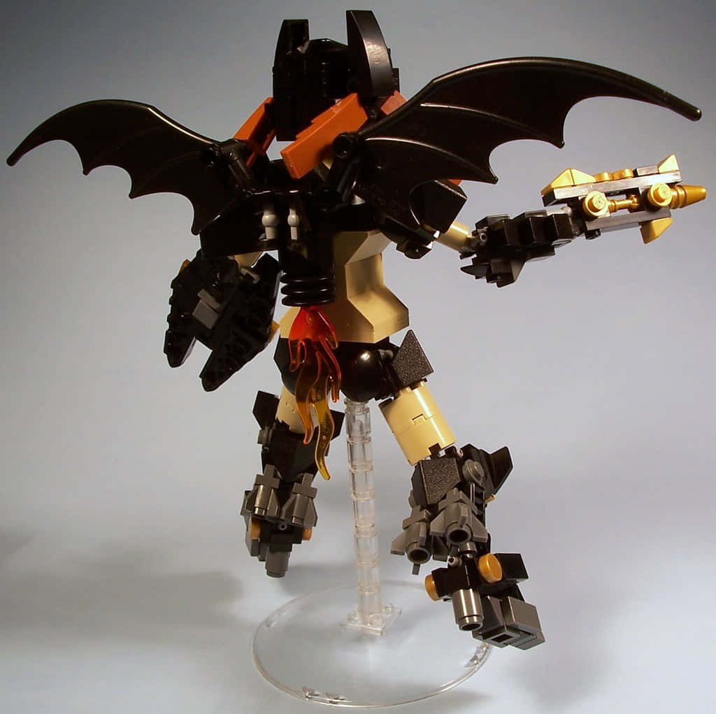 Batwing 桌布 壁紙 — 一個帶有蝙蝠翼的黑色和橙色LEGO機甲，手持金色武器，在純灰色背景前擺出威嚇姿態。