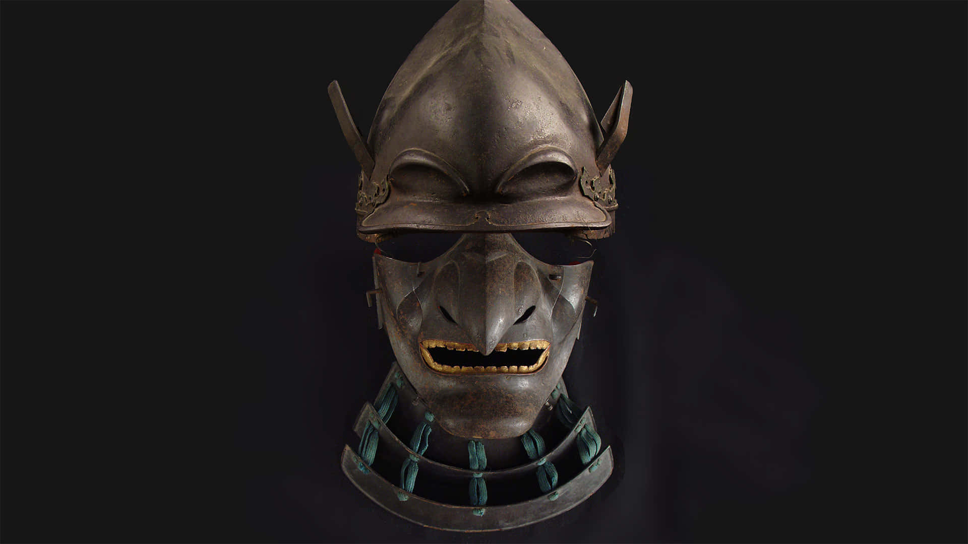 Samurai Helmet 桌布 壁紙 — 一個帶有金牙和角狀面罩的威嚇性武士頭盔，背景為深色。