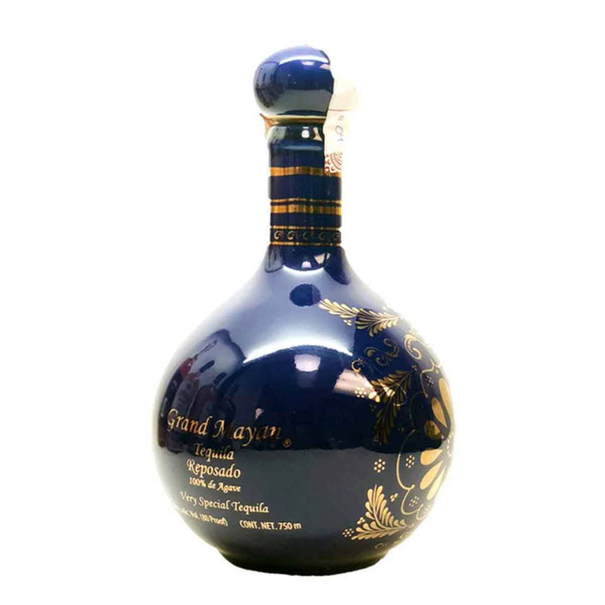alcohol 桌布 壁紙 — 一個帶有金箔圖案和文字的亮面深藍色龍舌蘭酒瓶，矗立在純白色背景前。