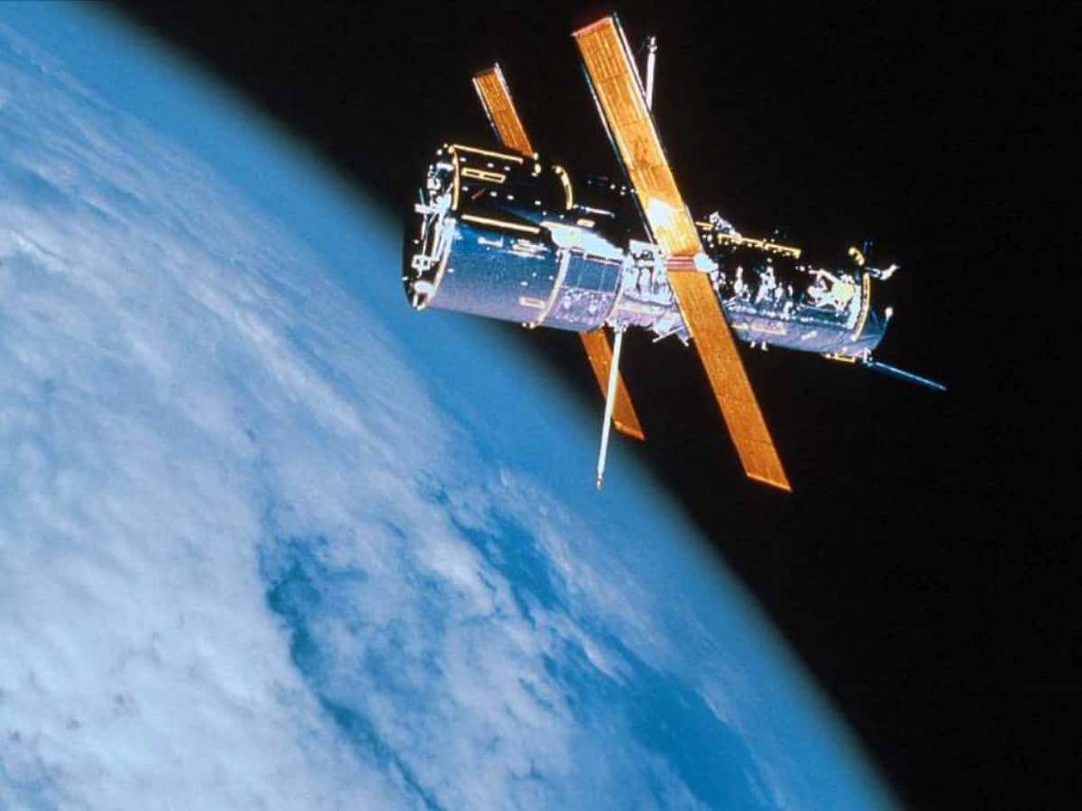 Hubble Space Telescope 桌布 壁紙 — 一個帶有金色太陽能板的太空望遠鏡，在漆黑的太空中繞地球運行。