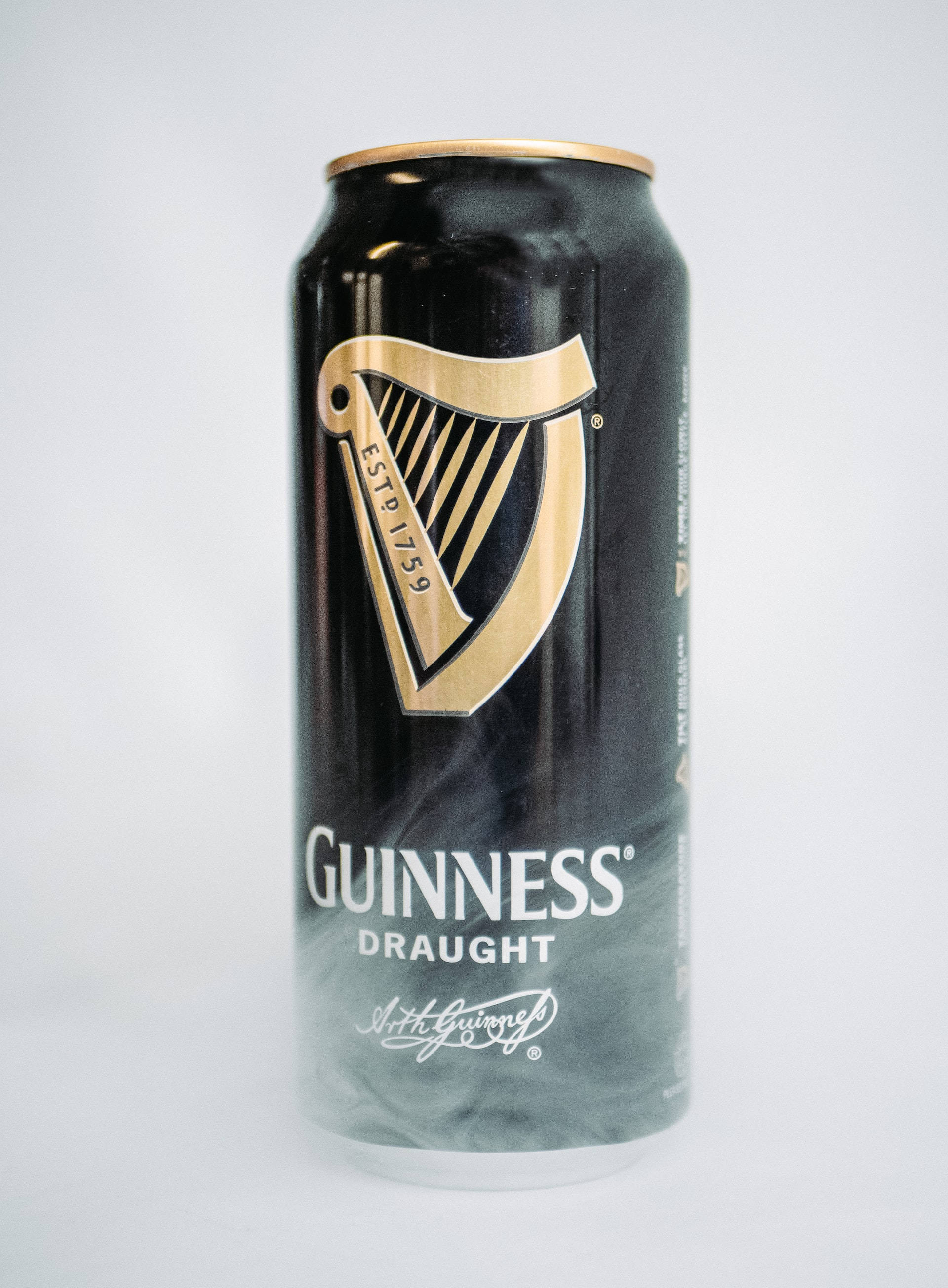 Beer 桌布 壁紙 — 一個帶有金色豎琴標誌的時尚黑色健力士生啤罐，居中放置在純白色背景上。
