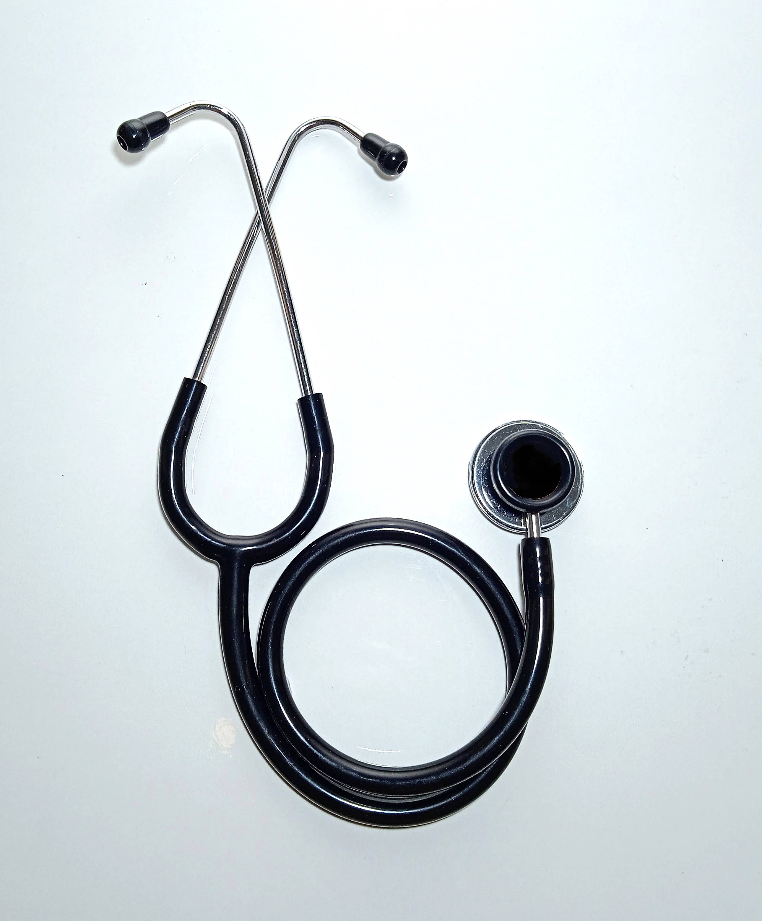 Stethoscope 桌布 壁紙 — 一個帶有鉻色裝飾的黑色聽診器盤繞在白色平面上，突顯其醫療用途和時尚設計。