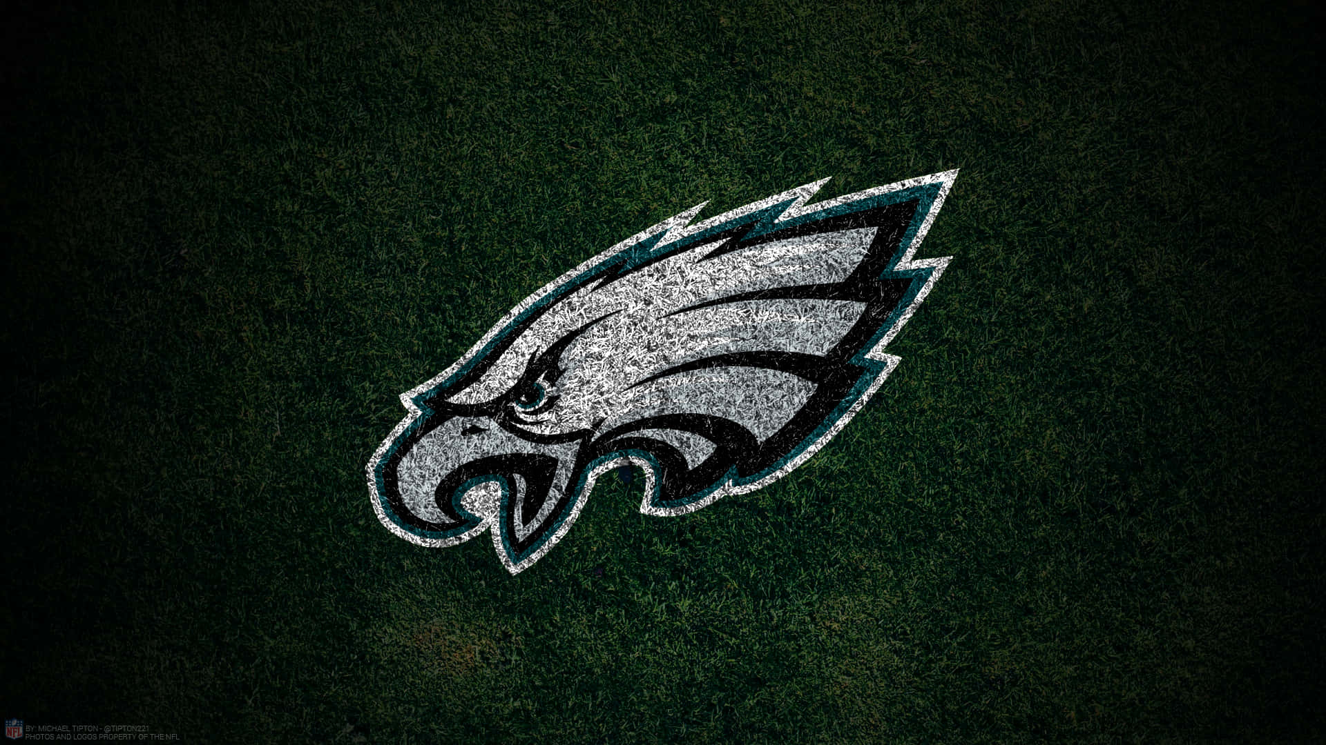 Eagles Football 桌布 壁紙 — 一個帶有銀色和藍綠色細節的粗獷費城老鷹標誌，在深綠色草地紋理上脫穎而出。