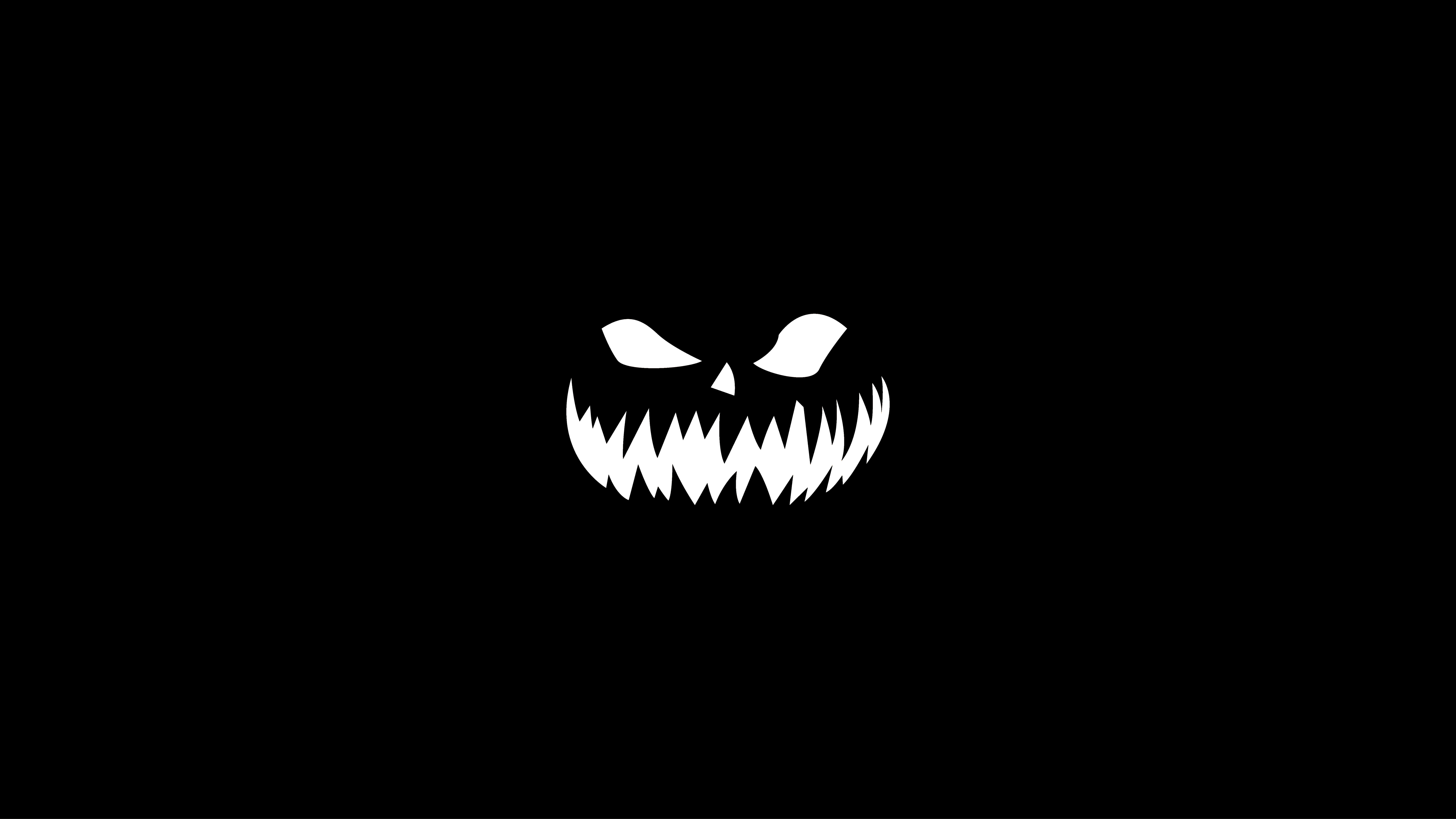 Minimalist Monochrome 桌布 壁紙 — 一個帶有鋸齒狀牙齒和狹窄眼睛的 stark 白色極簡主義南瓜燈面孔，在純黑色背景上怒視。