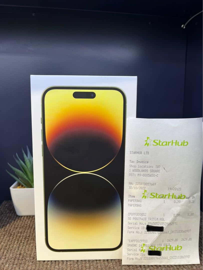 iPhone 桌布 壁紙 — 一個帶有鮮豔漸層桌布的新iPhone盒，旁邊有一張StarHub收據和一個小盆栽多肉植物，放在有紋理的表面上。