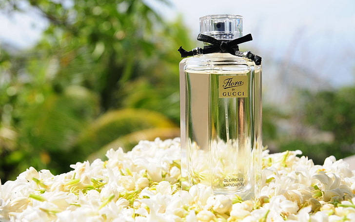 Gucci Flora香水瓶被白色茉莉花環繞，在明亮的陽光下。