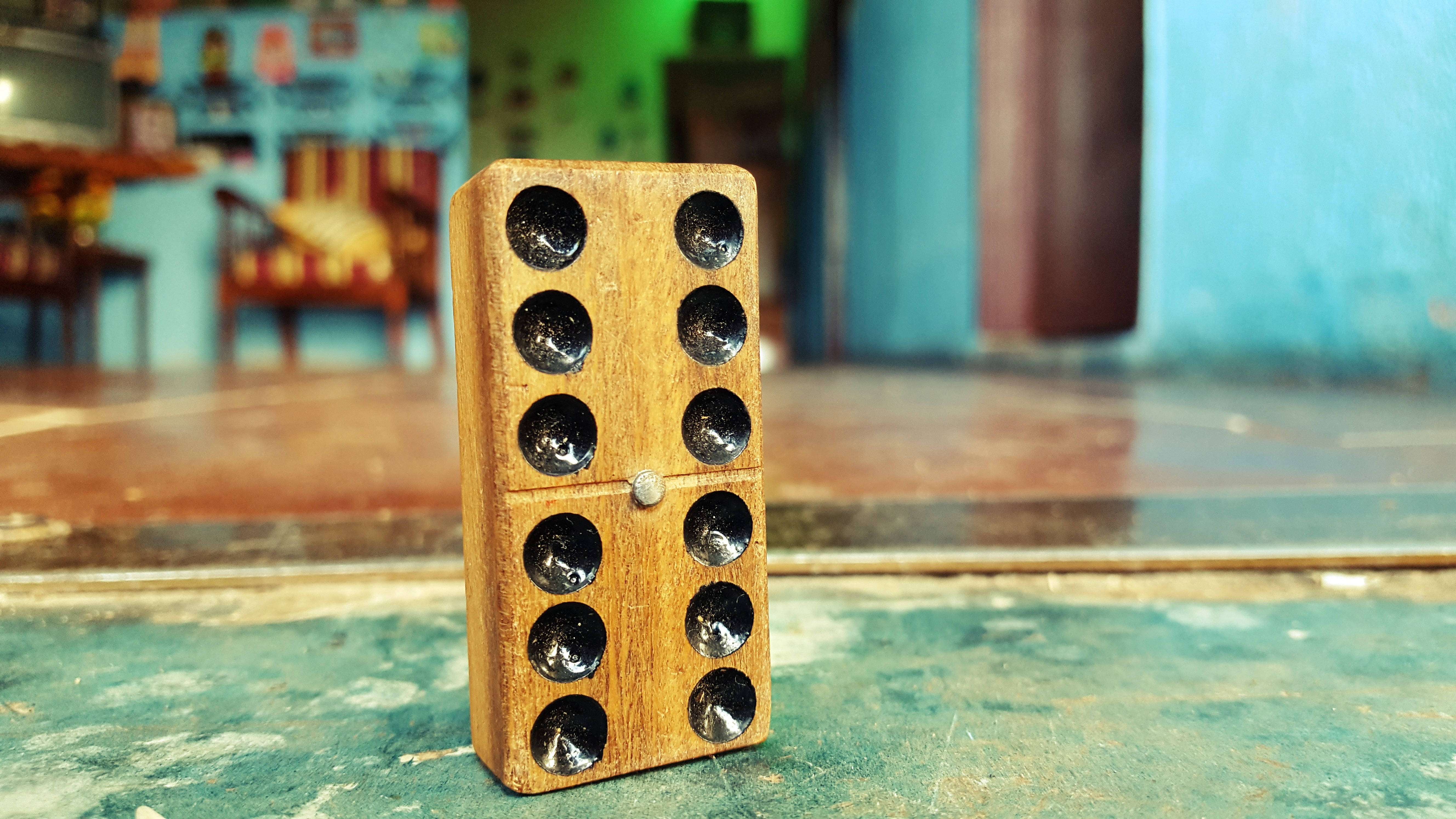 Domino 桌布 壁紙 — 一個帶有黑色點的木製骨牌直立於風化的綠色表面上，背景是色彩繽紛且模糊的。