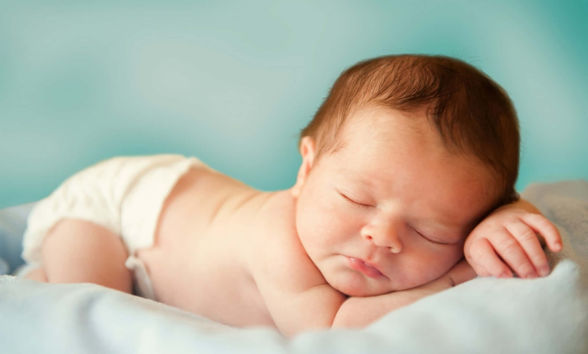 Infant 桌布 壁紙 — 一個平靜的新生嬰兒在柔軟的毯子上安睡，背景是寧靜的藍綠色。