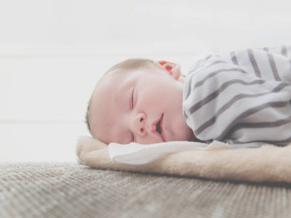 Baby Boy 桌布 壁紙 — 一個平靜的新生嬰兒在柔軟的毯子上閉著眼睛、嘴巴微張，安穩地睡著。