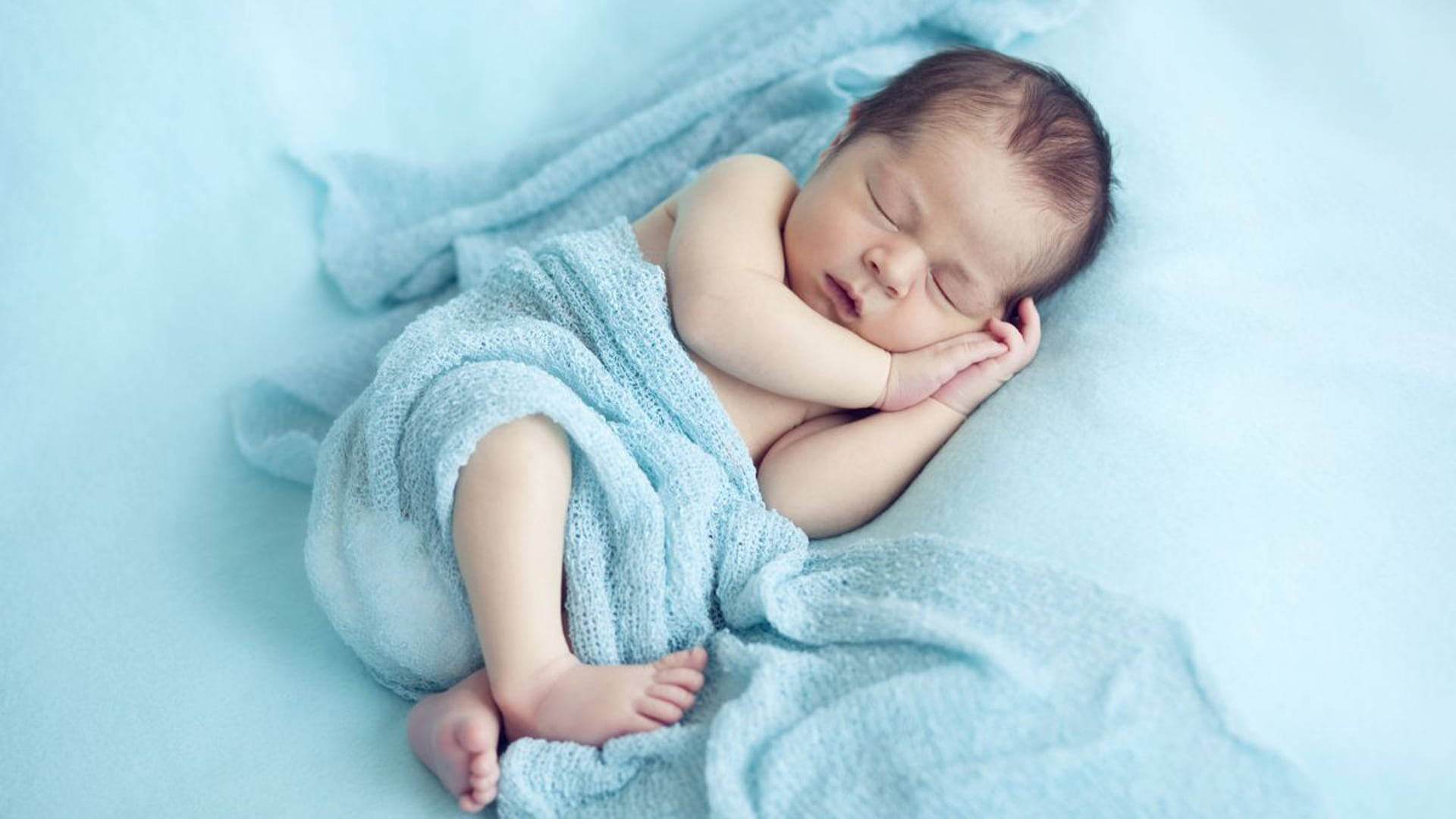 Very Cute Baby 桌布 壁紙 — 一個平靜的新生嬰兒被柔軟的藍色針織布包裹著，睡在相配的毯子上，睡得很安穩。