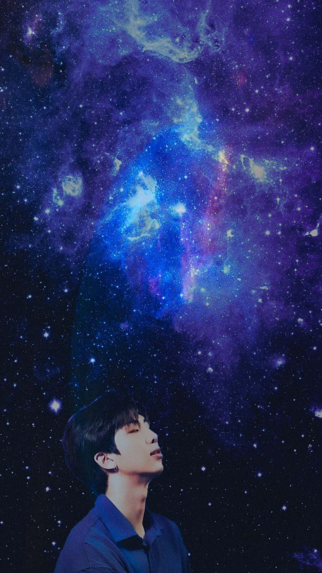 BTS 桌布 壁紙 — 一個年輕人在充滿旋轉藍色、紫色和發光星星的充滿活力的宇宙星雲下驚奇地向上凝視。