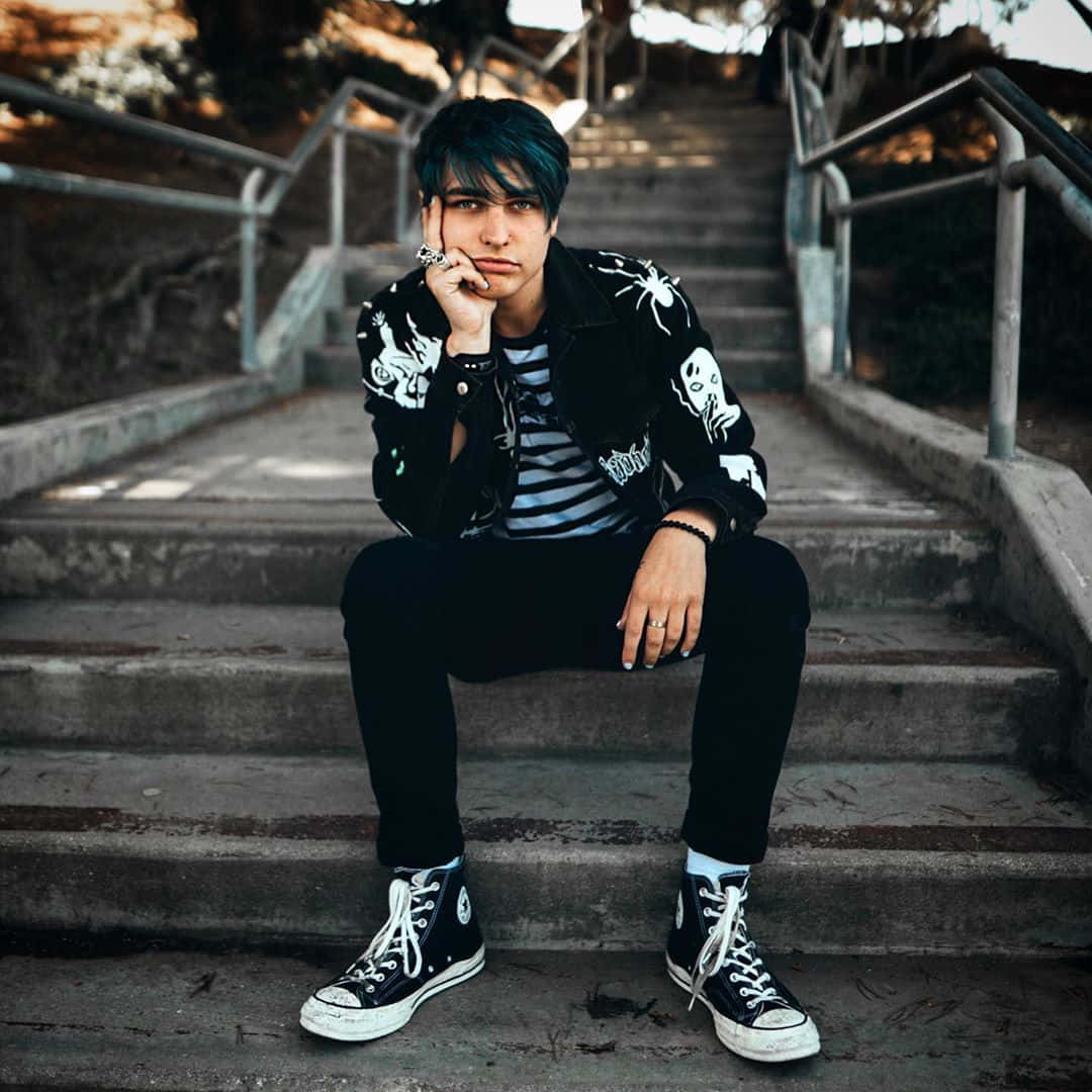 Colby Brock 桌布 壁紙 — 一個年輕人有青綠色頭髮，穿著骷髏外套和黑色Converse，沉思地坐在混凝土樓梯上。