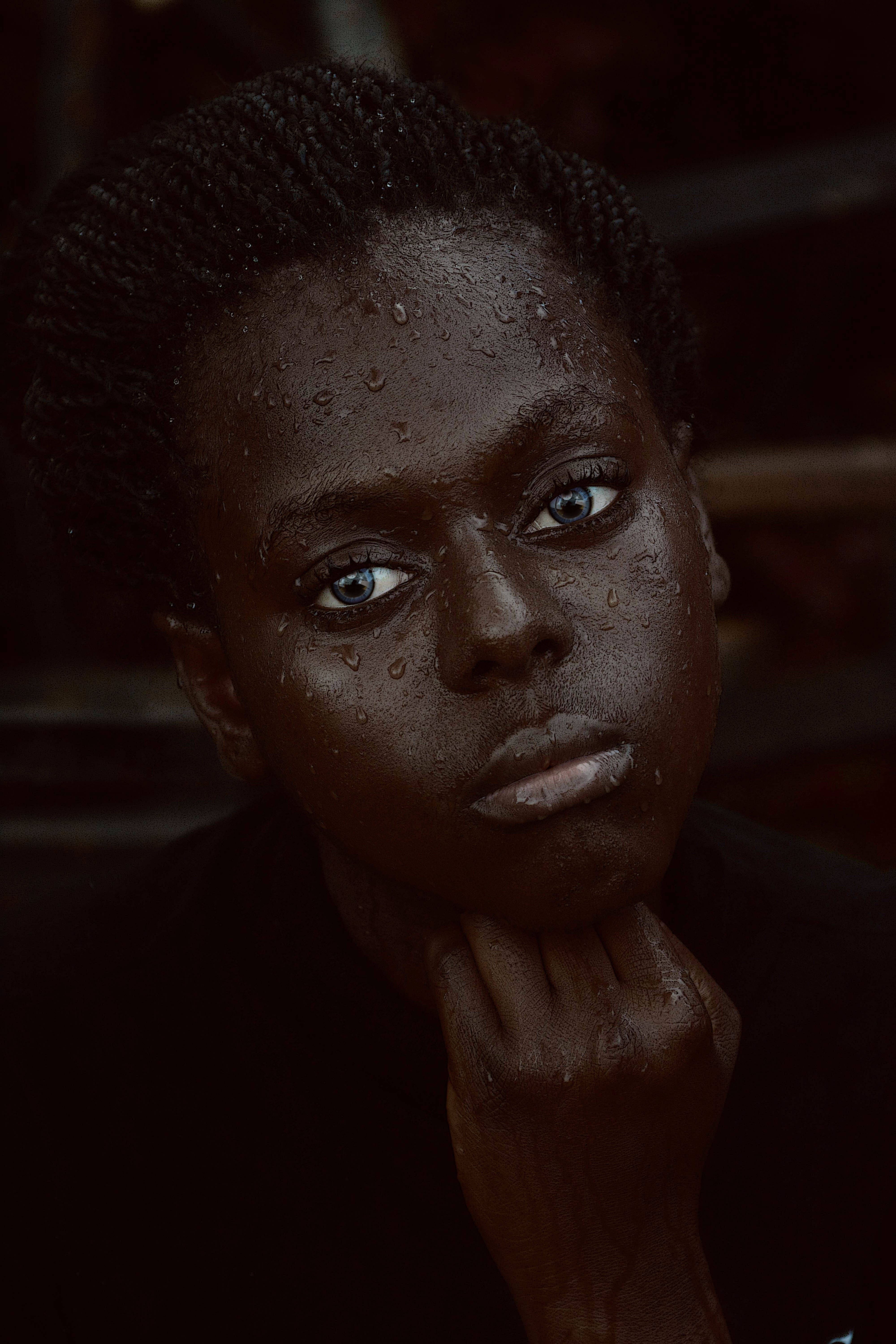Black Girl 桌布 壁紙 — 一個年輕人的特寫肖像，深色皮膚，辮子頭髮上閃爍著水珠，專注地凝視著相機。