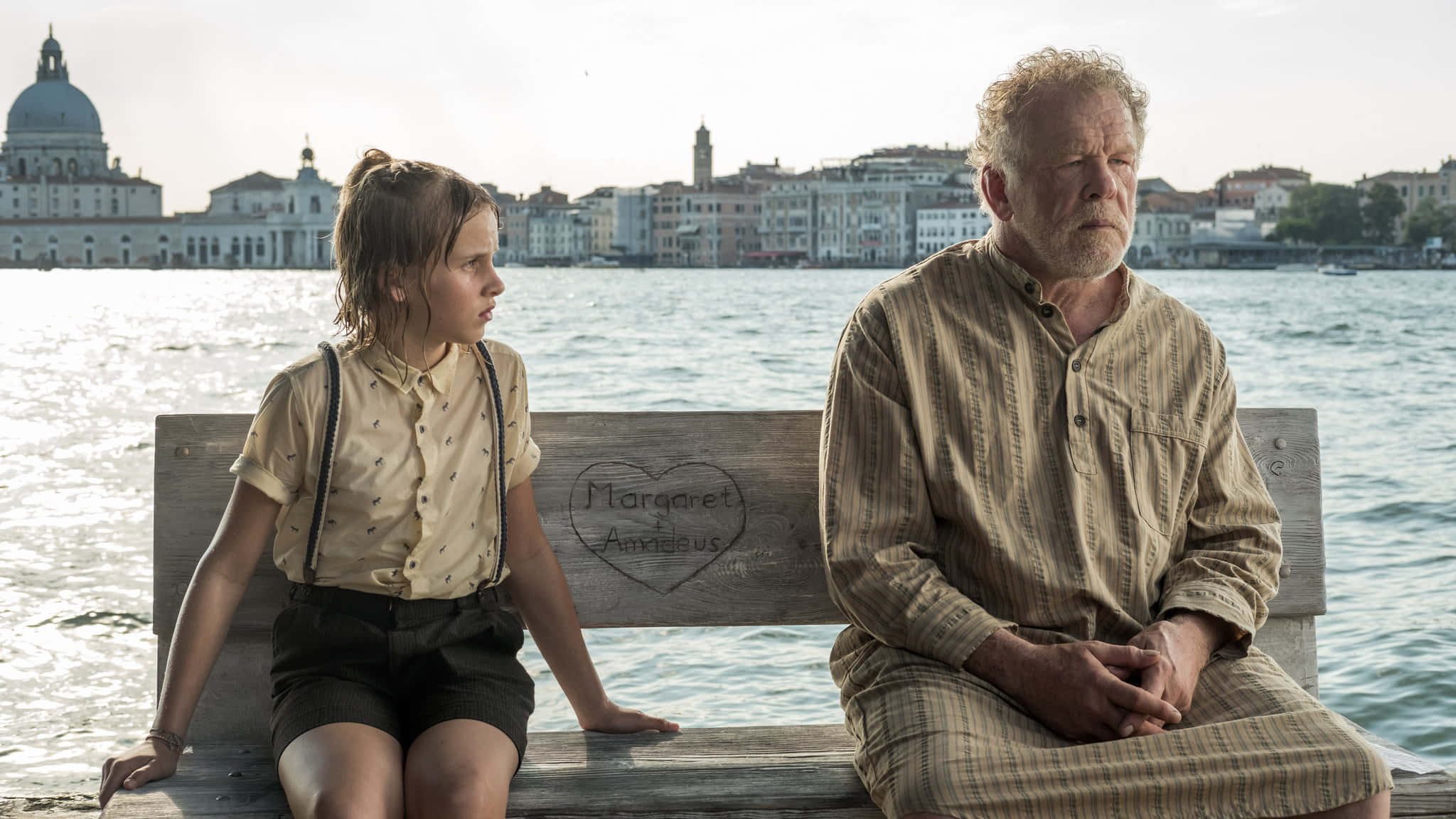 Nick Nolte 桌布 壁紙 — 一個年輕女孩和一位年長男士坐在水邊的木長椅上，背景是歷史悠久的威尼斯建築。