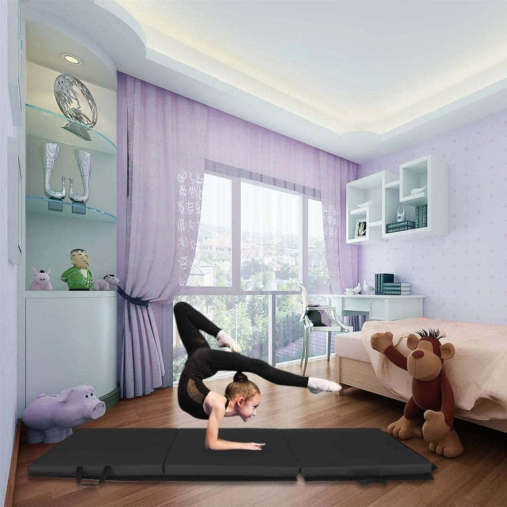 Gymnastics Mat 桌布 壁紙 — 一個年輕女孩在明亮的紫色主題臥室裡，在大窗戶和毛絨玩具旁，於黑色瑜伽墊上做出動態瑜伽姿勢。