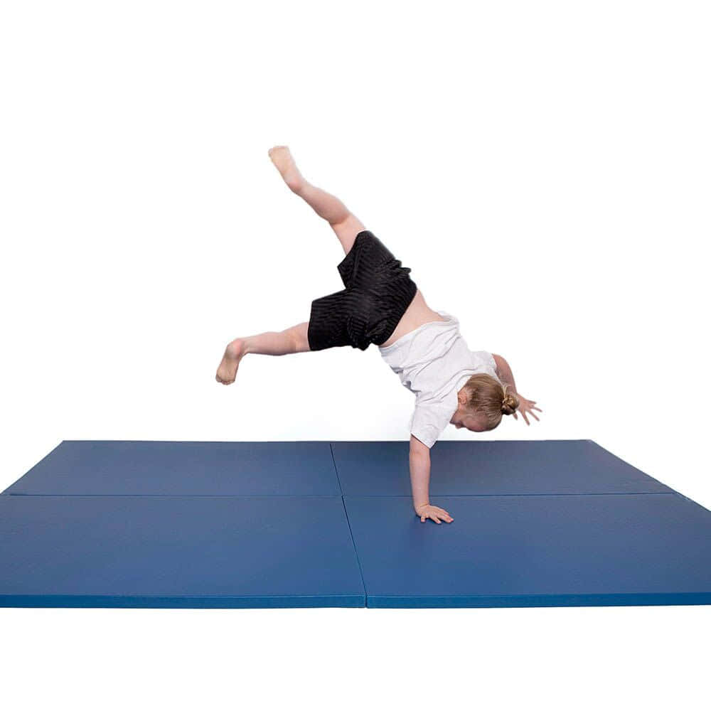 Gymnastics Mat 桌布 壁紙 — 一個年輕女孩在藍色體操墊上做出動態的倒立動作，背景是純白色。