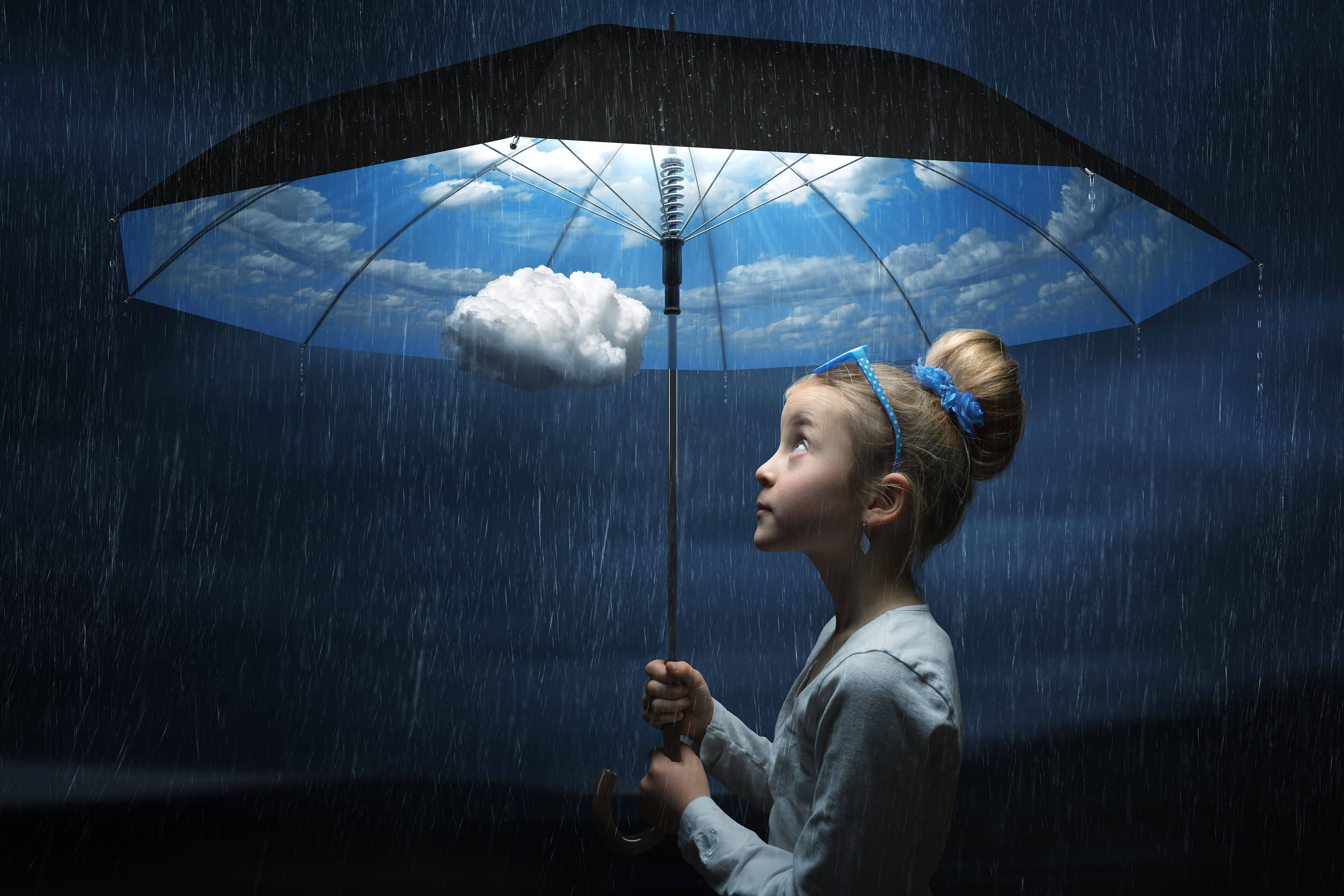 創意 桌布 壁紙 — 一個年輕女孩拿著一把黑色雨傘，露出明亮的藍天和蓬鬆的雲朵，周圍下著雨，環境陰暗。