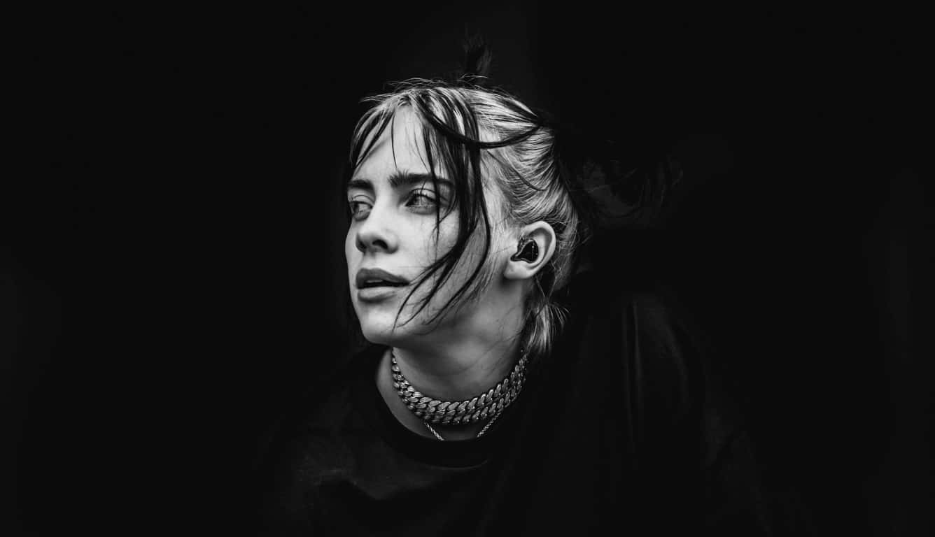 Billie Eilish Laptop 桌布 壁紙 — 一個年輕女性的黑白肖像，濕頭髮和鏈條項鍊，背景是深色。