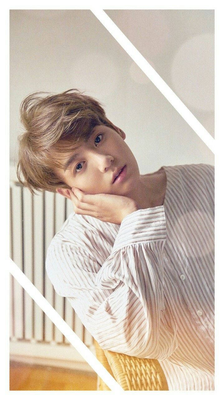 Jungkook 桌布 壁紙 — 一個年輕男子，一頭凌亂的金髮，穿著條紋襯衫，在柔和光線的室內環境中，用手托著下巴。