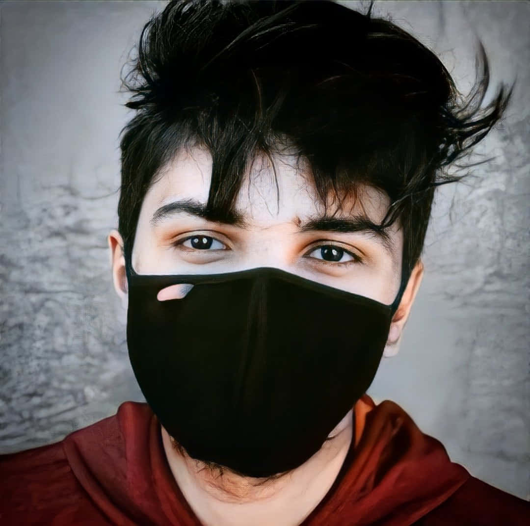 Instagram Profile 桌布 壁紙 — 一個年輕男子，一頭凌亂的黑髮和銳利的眼神，透過黑色口罩凝視著紋理灰牆。