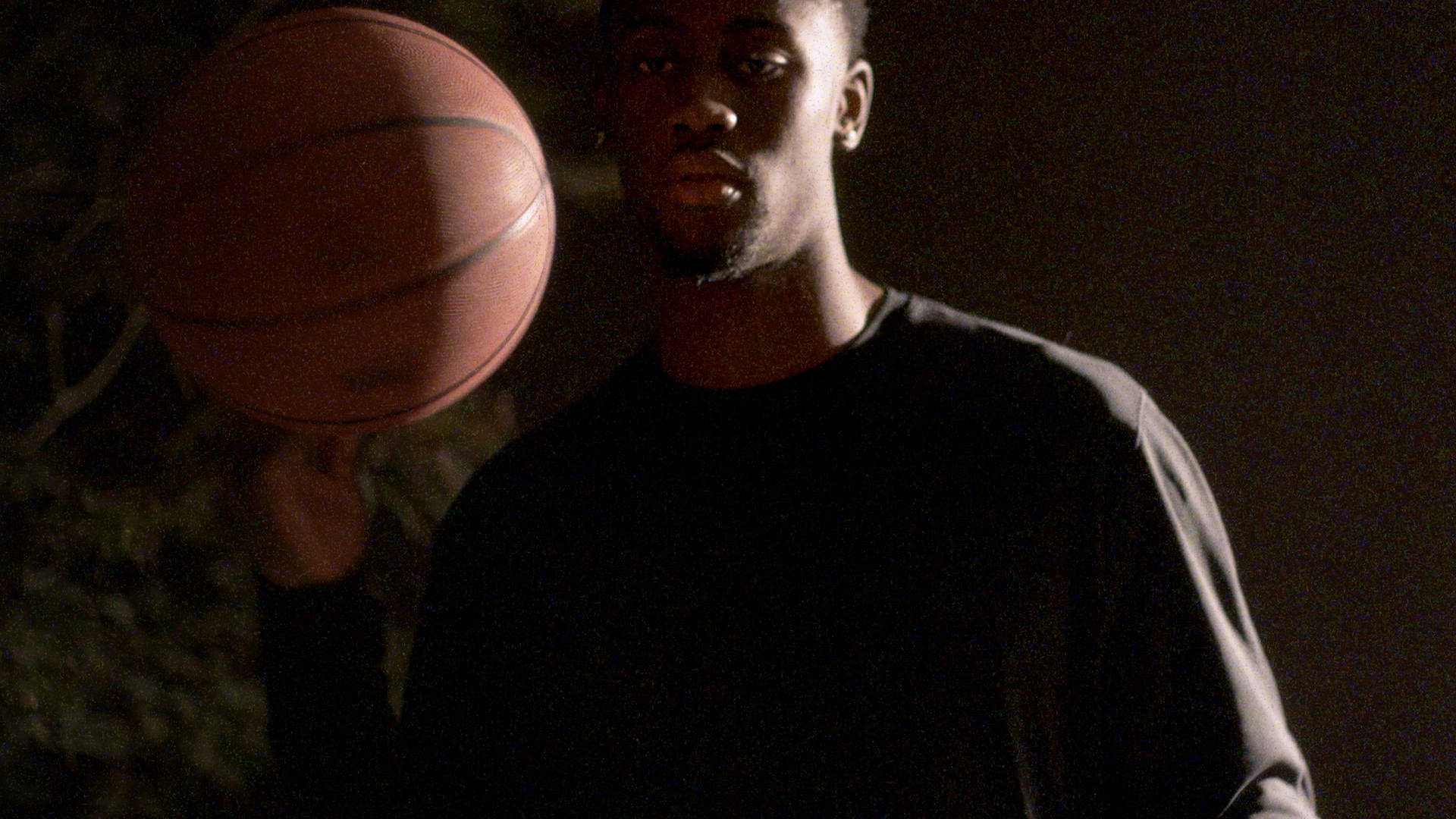 caris levert 桌布 壁紙 — 一個年輕男子在昏暗的夜間燈光下，專注地拿著一個籃球。