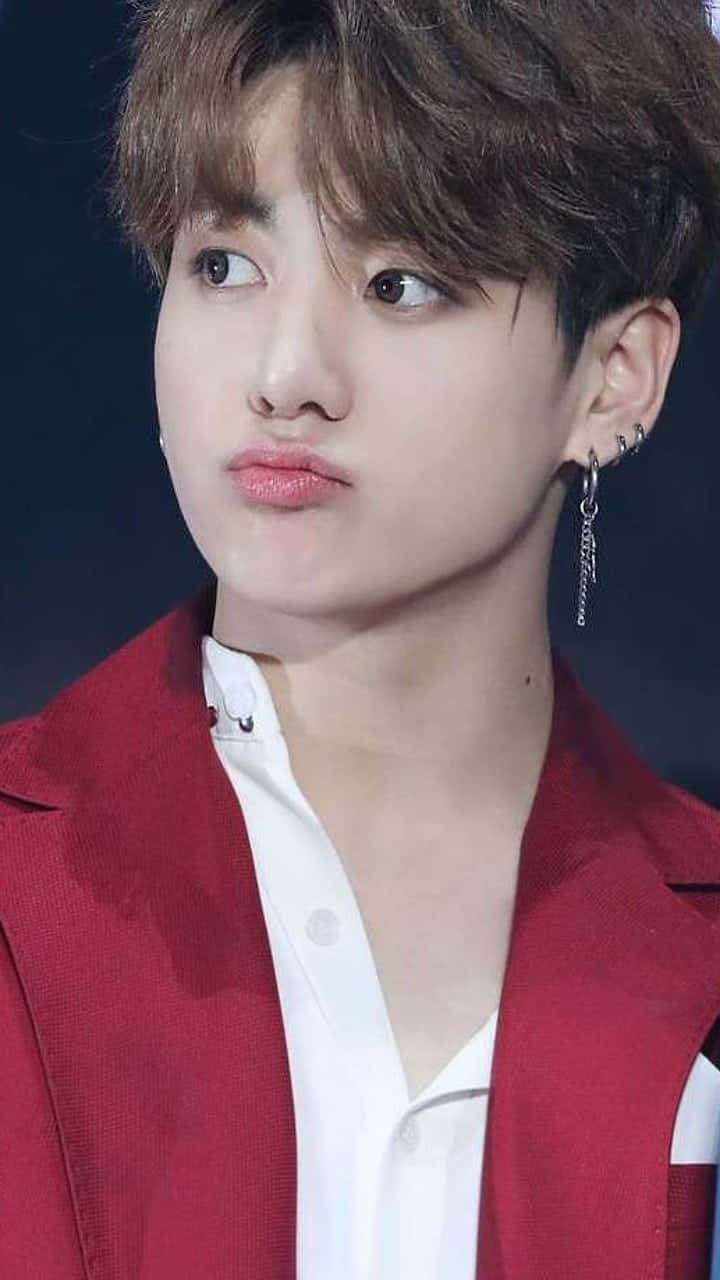 Jungkook 桌布 壁紙 — 一個年輕男子的特寫肖像，他有亂糟糟的棕色頭髮，穿著紅色西裝外套和白色襯衫，背景是黑色。