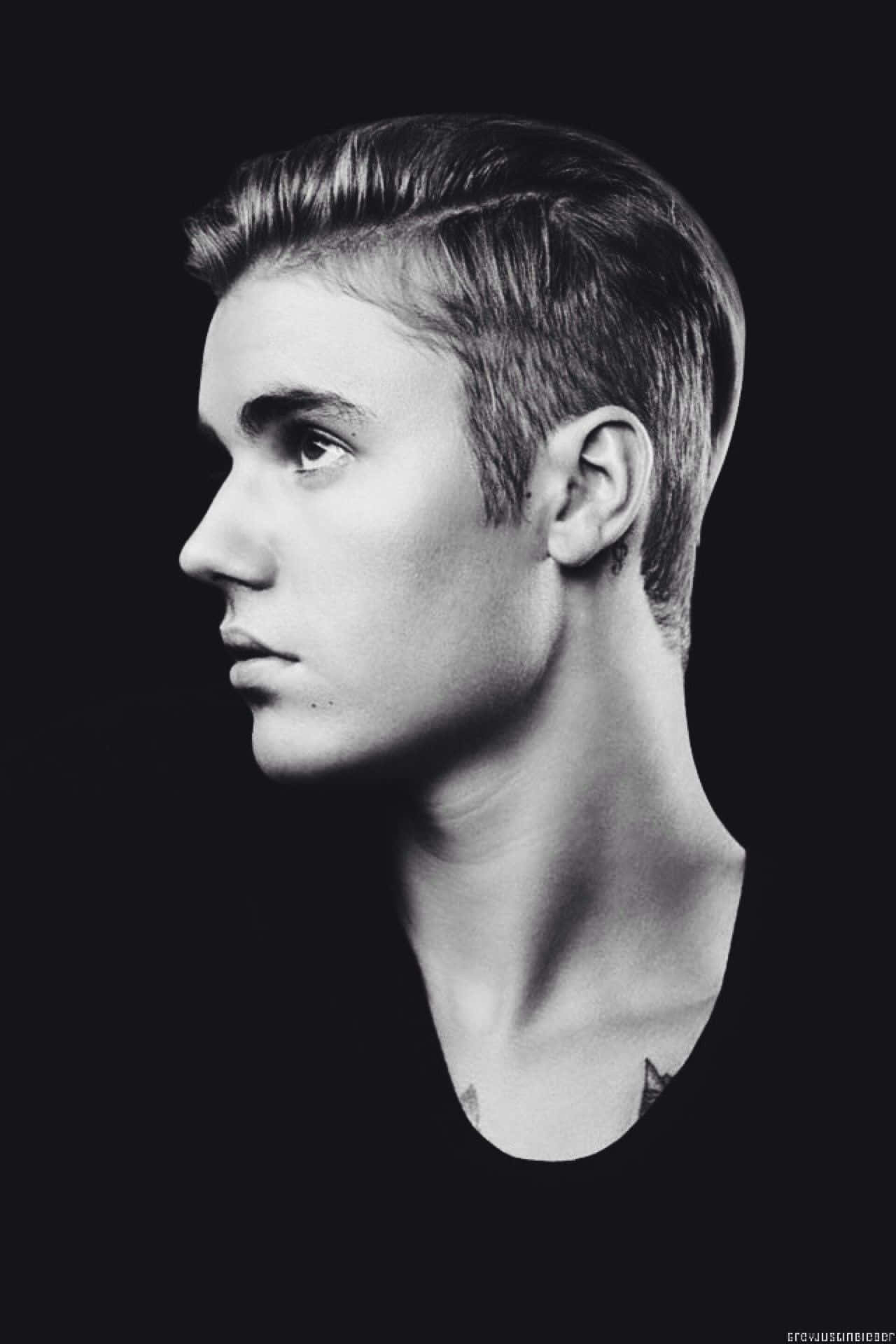 Justin Bieber 2021 桌布 壁紙 — 一個年輕男子的黑白側面肖像，背景黑暗，柔和光線突出他的面部特徵和頭髮。