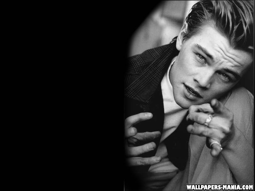 Dicaprio 桌布 壁紙 — 一個年輕男子的黑白肖像，眼神強烈，在黑暗背景中向前指著。