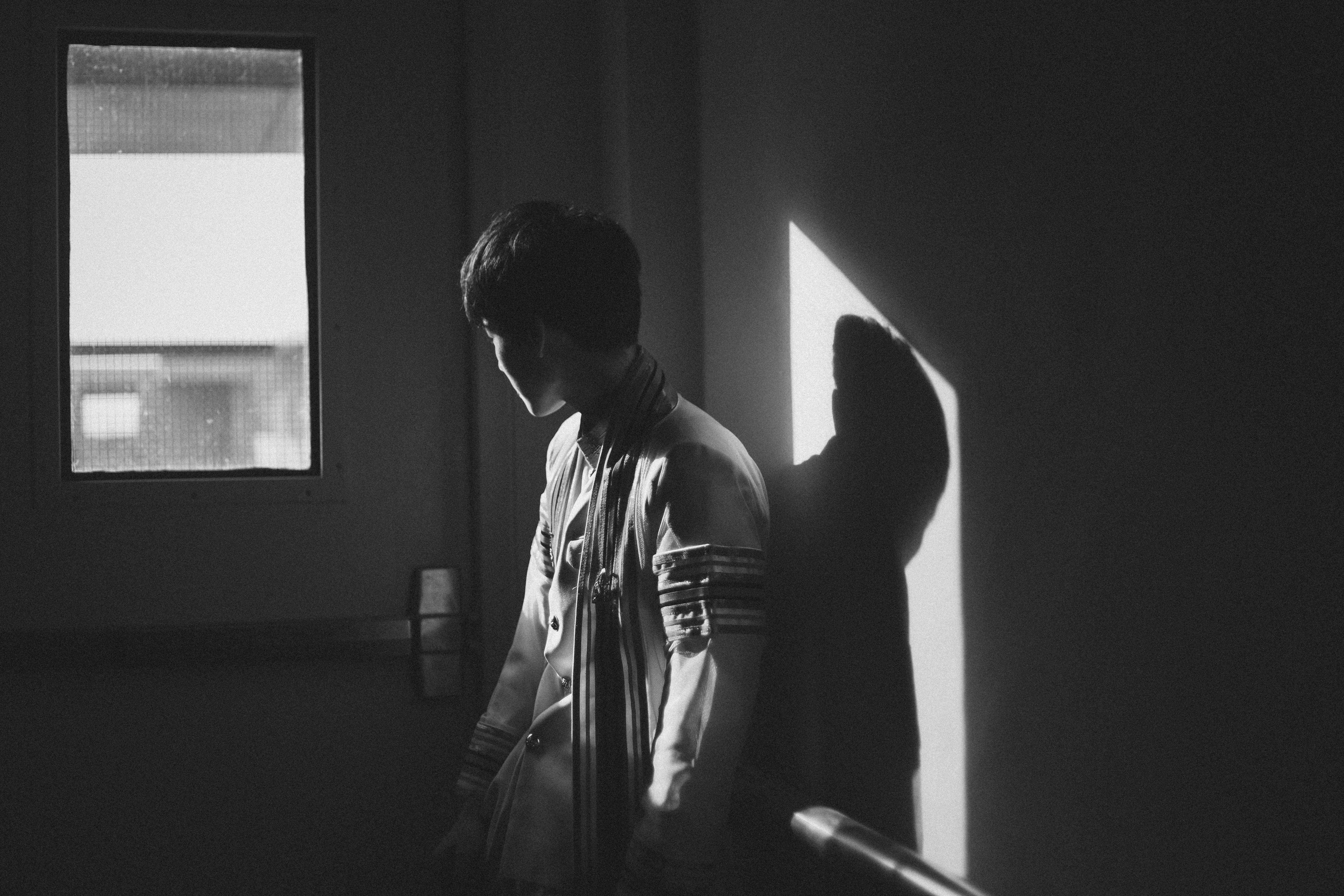 Boy 桌布 壁紙 — 一個年輕男子站在昏暗的房間中，他的剪影由窗戶斜射進來的光束投射出來。