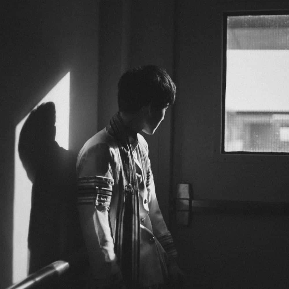 Sad Profile 桌布 壁紙 — 一個年輕男子站在昏暗的房間中，強烈的窗光投射出他的剪影，並以單色凸顯他的側面輪廓。