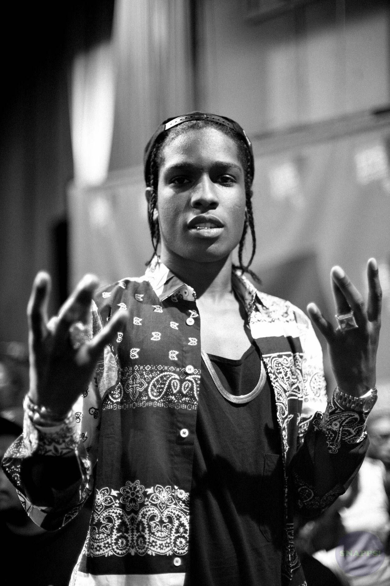 rocky 桌布 壁紙 — 一個年輕男子紮辮子、穿著圖案襯衫、雙手做手勢的黑白肖像。