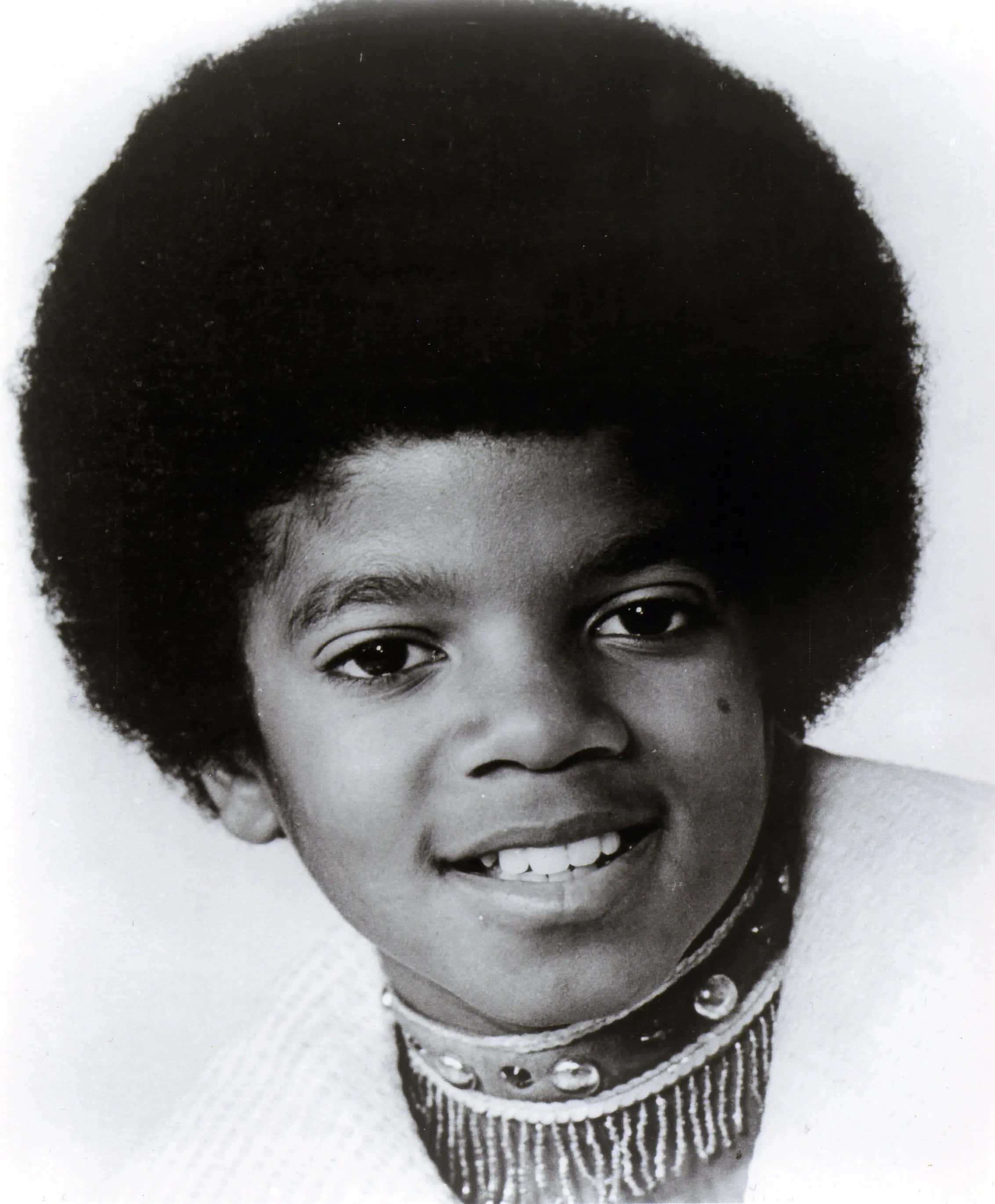 Young Michael Jackson 桌布 壁紙 — 一個年輕男孩的大爆炸頭黑白肖像，對著鏡頭溫暖微笑。