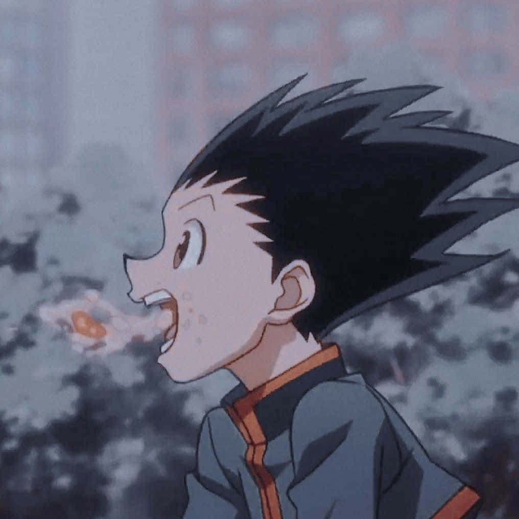 獵人 x 獵人 桌布 壁紙 — 一個年輕的動漫男孩，有著刺蝟般的黑色頭髮，在模糊的城市背景下噴火吶喊。