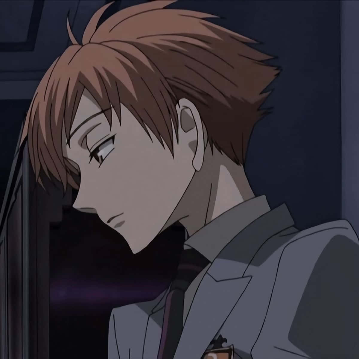 Kaoru Hitachiin 桌布 壁紙 — 一個年輕的動畫男性，有著凌亂的棕色頭髮和校服，在昏暗的房間裡低頭沉思。