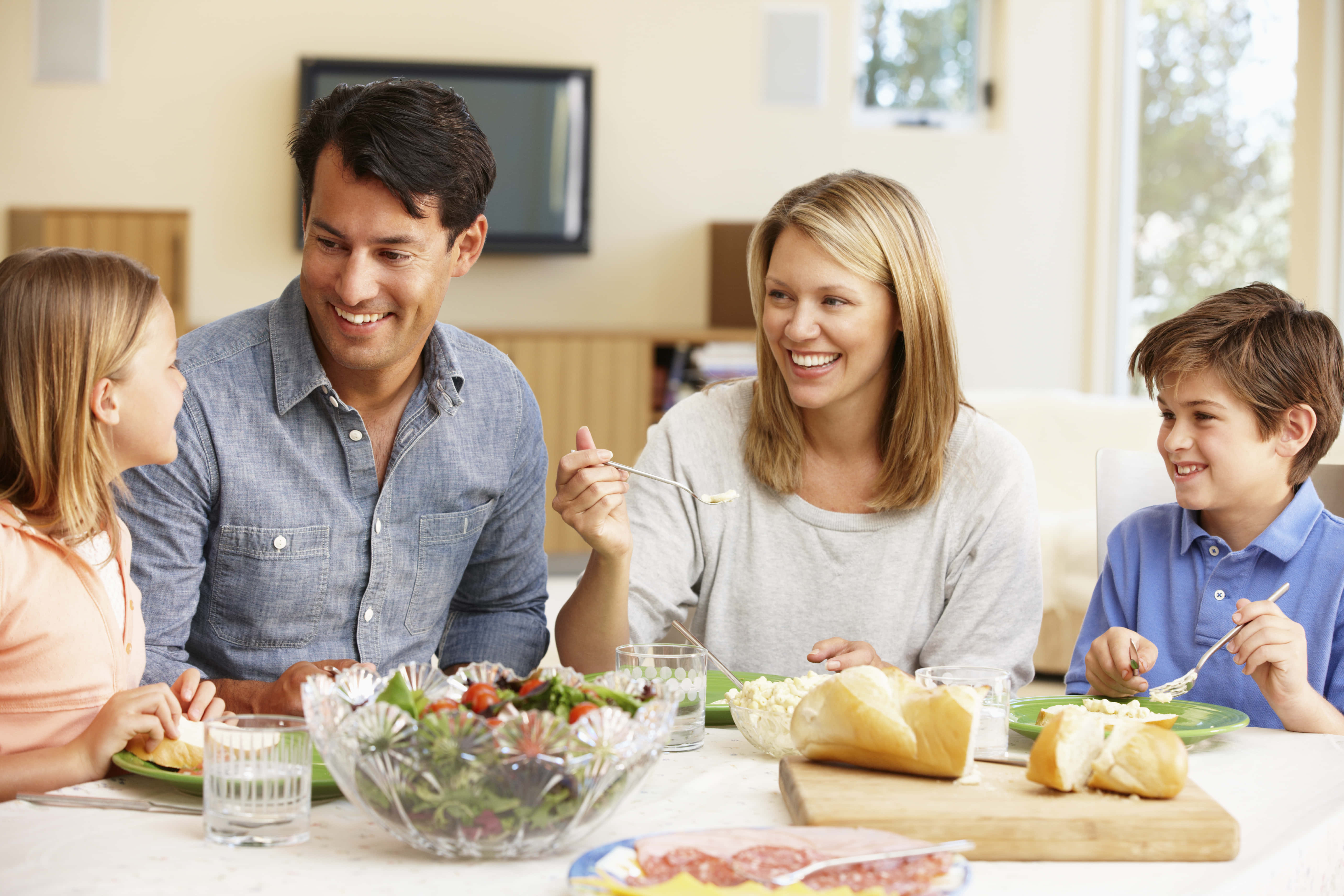 快樂 桌布 壁紙 — 一個幸福的四口之家在擺滿新鮮食物和歡笑的餐桌上共享一頓溫馨的晚餐。