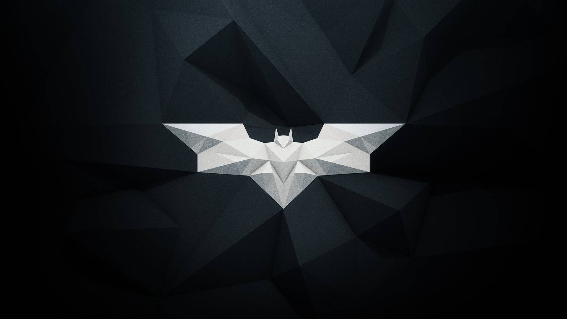 Dc Comics Batman 桌布 壁紙 — 一個幾何白色蝙蝠符號在帶有銳利角狀陰影的深色多邊形背景上發光。