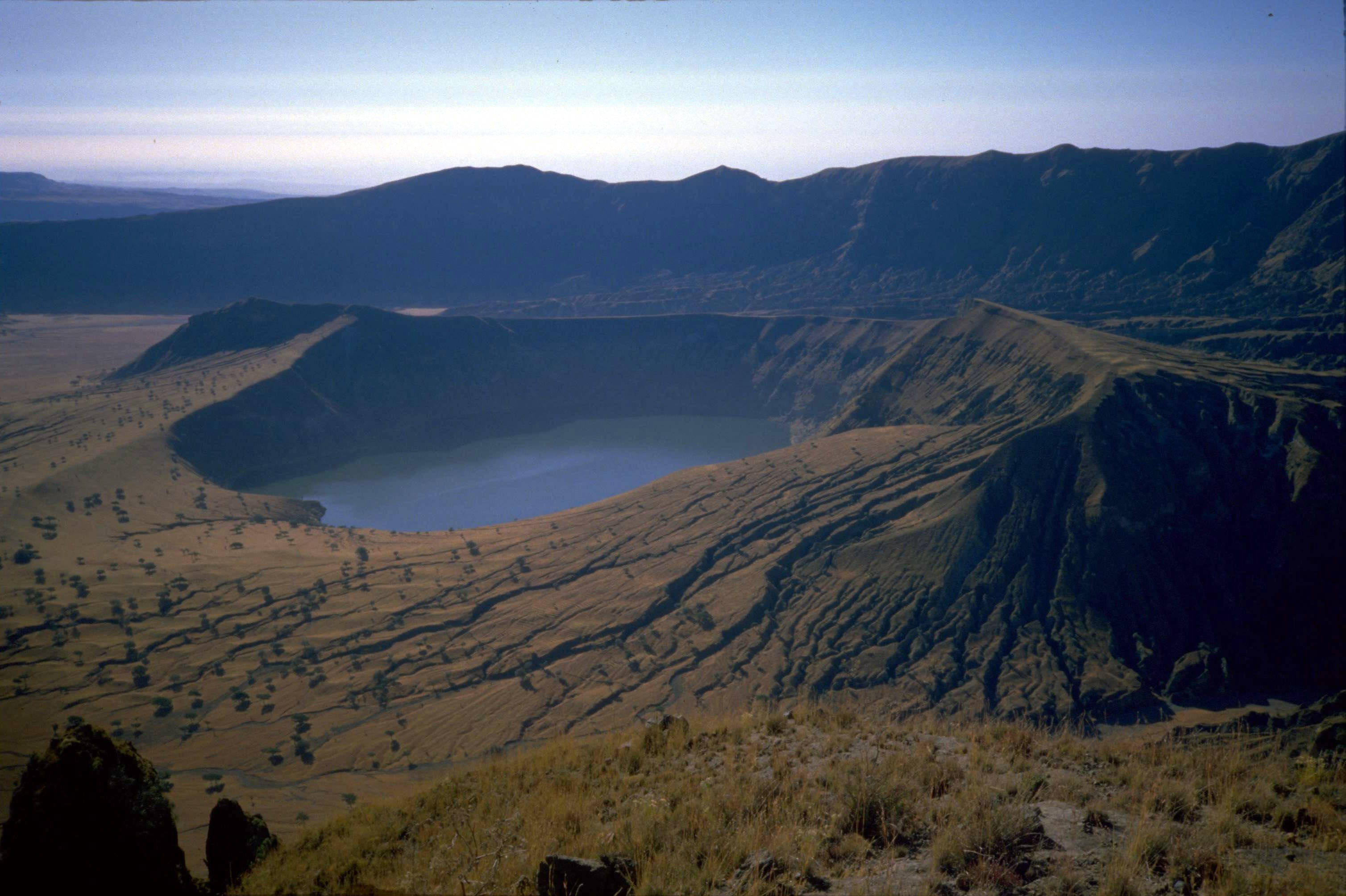 Sudan 桌布 壁紙 — 一個廣闊的火山口湖，坐落在崎嶇的大地色山丘中，在清澈的藍天下。