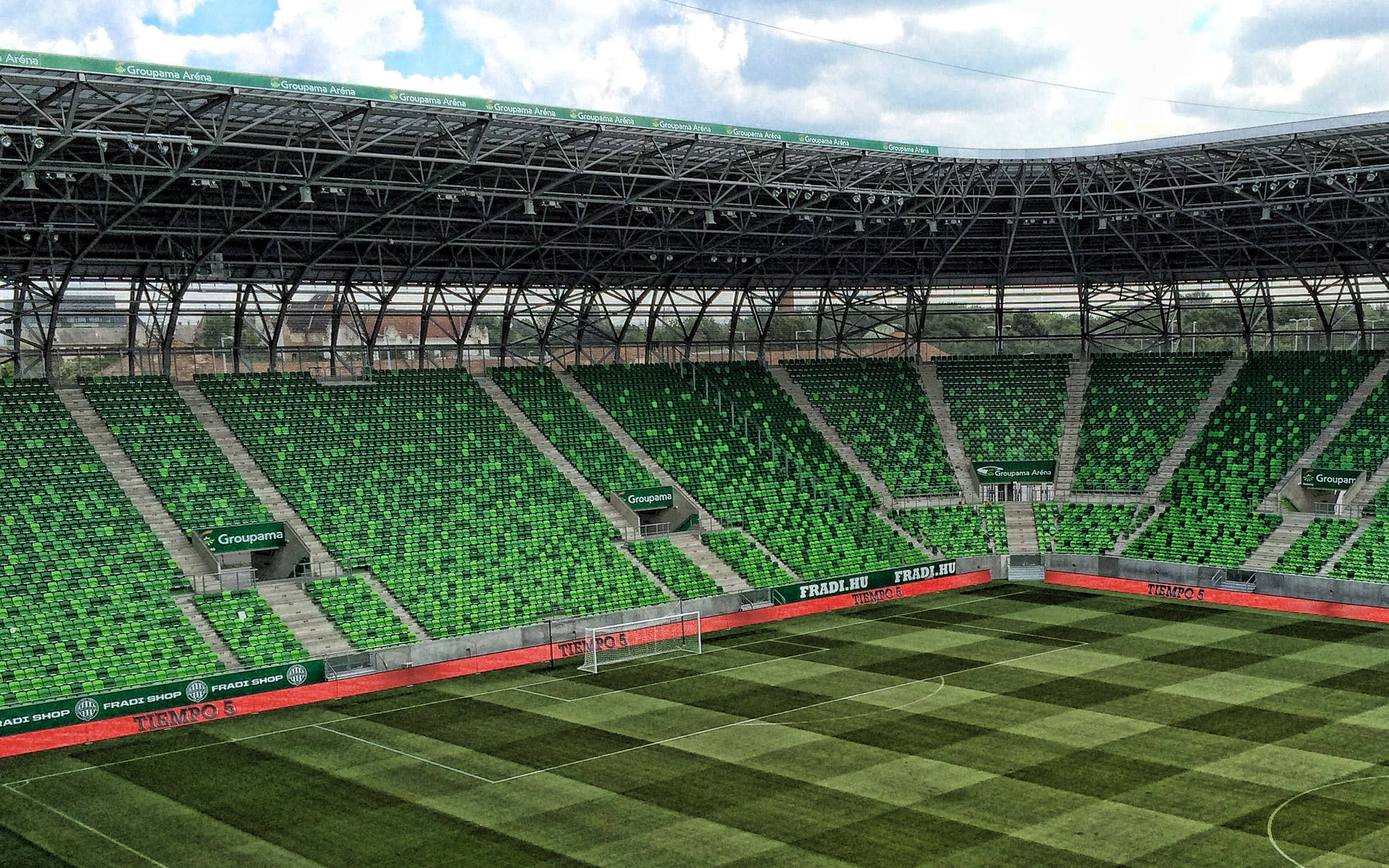 Stadium 桌布 壁紙 — 一個廣闊的空蕩蕩足球場，在陰天之下有充滿活力的綠色座位。