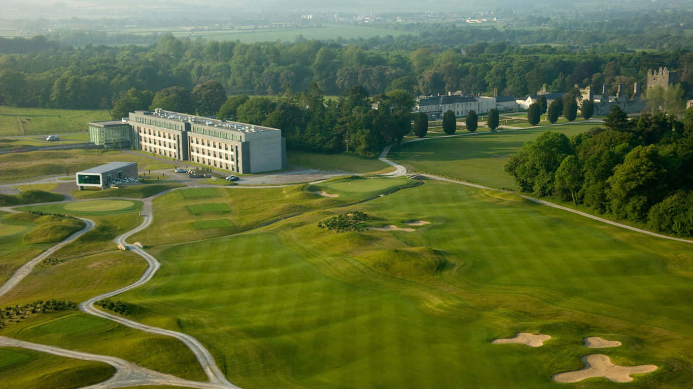 1366x768 Golf Course 桌布 壁紙 — 一個廣闊高爾夫球場的鳥瞰圖，設有修剪整齊的果嶺、沙坑和蜿蜒小徑，周圍環繞著茂密的森林和現代建築。